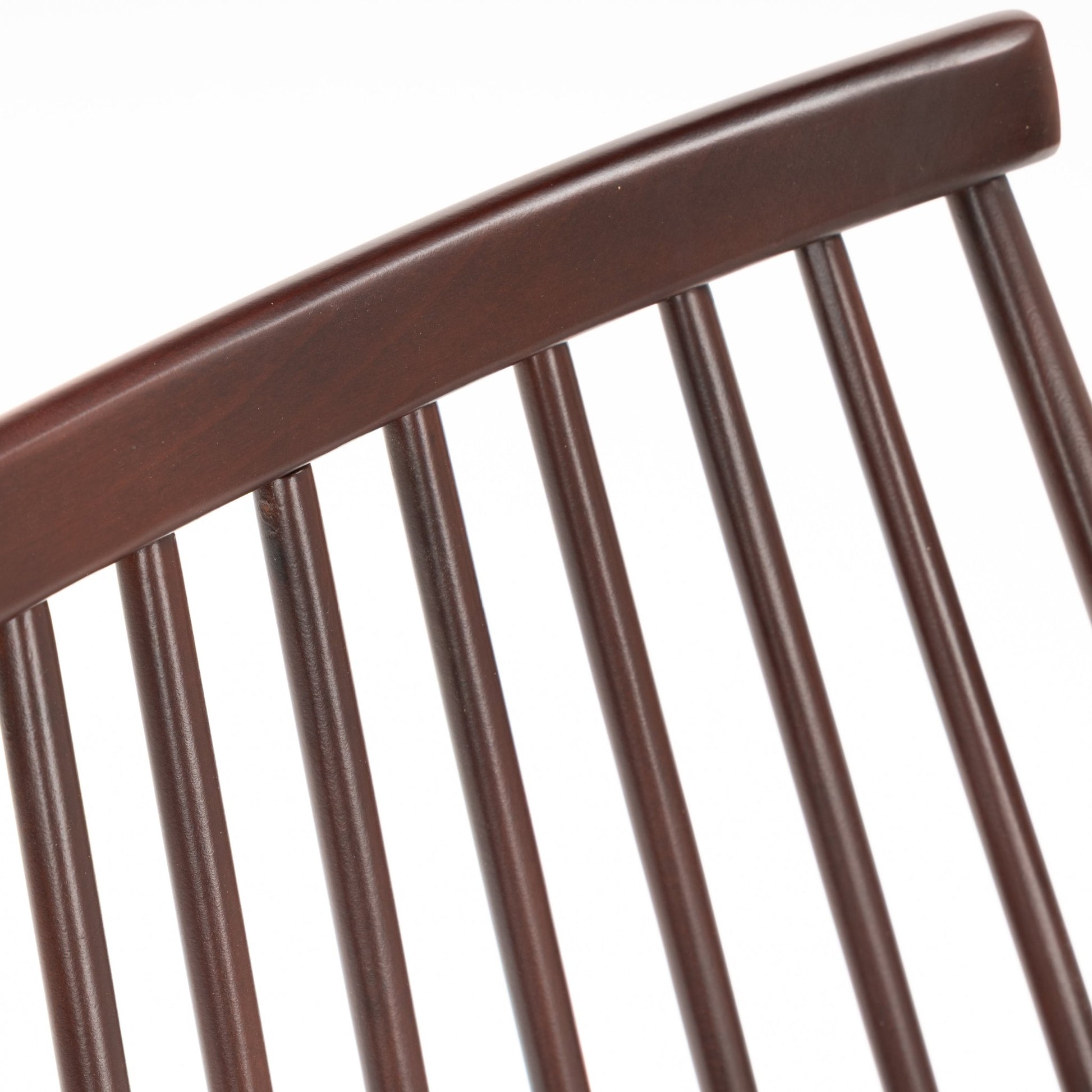 Close-up of dark brown wooden chair backrest with evenly spaced vertical dowel spindles and smooth curved top rail