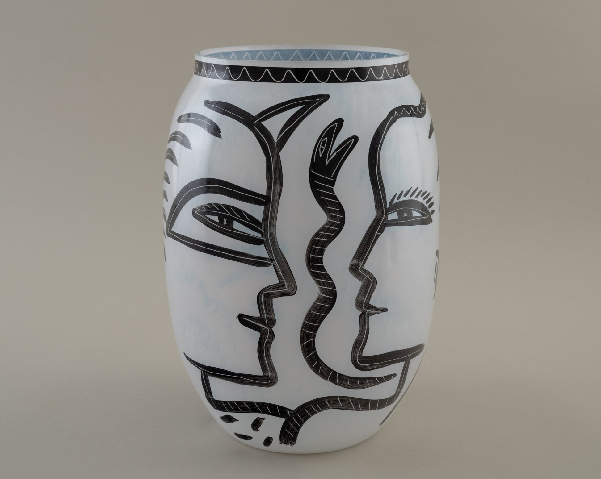 Ulrica Hydman-Vallien "Caramba" vase for Kosta Boda with black hand-painted faces and serpent motifs on white glass.