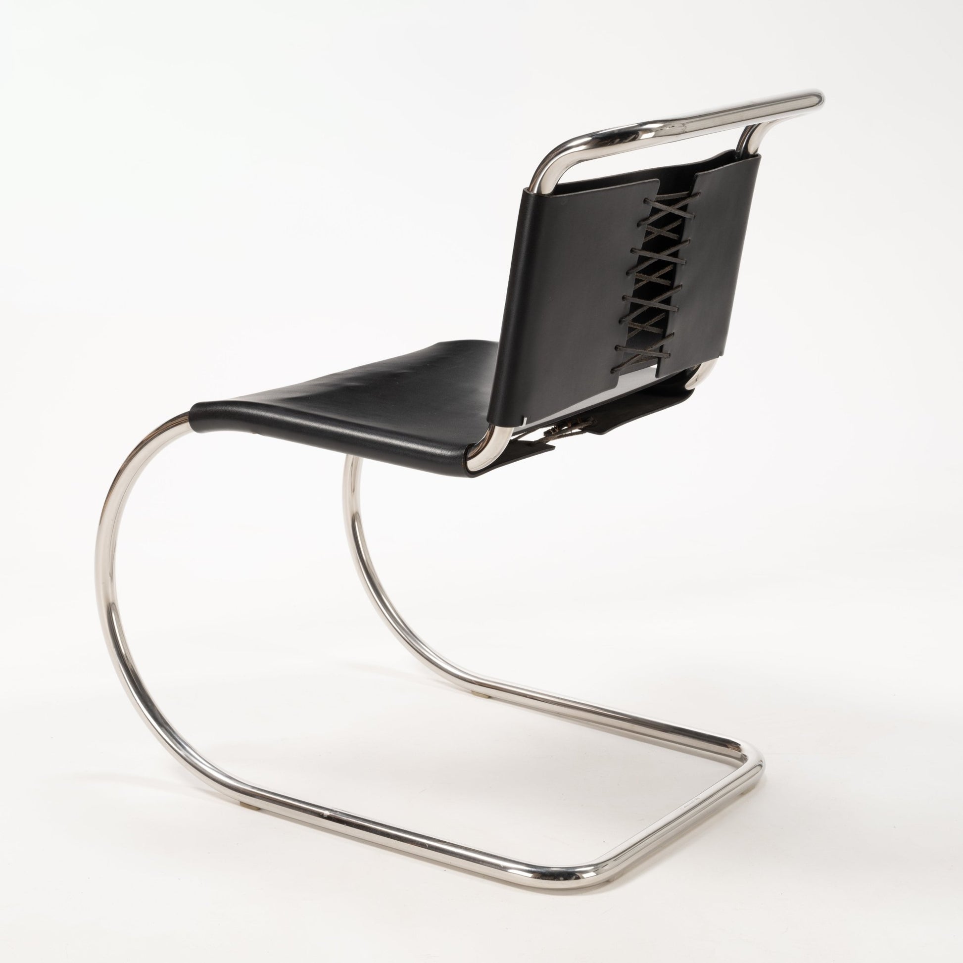 Rear angle of Van Der Rohe MR10 cantilever chair with polished chrome tubular frame and black leather laced backrest