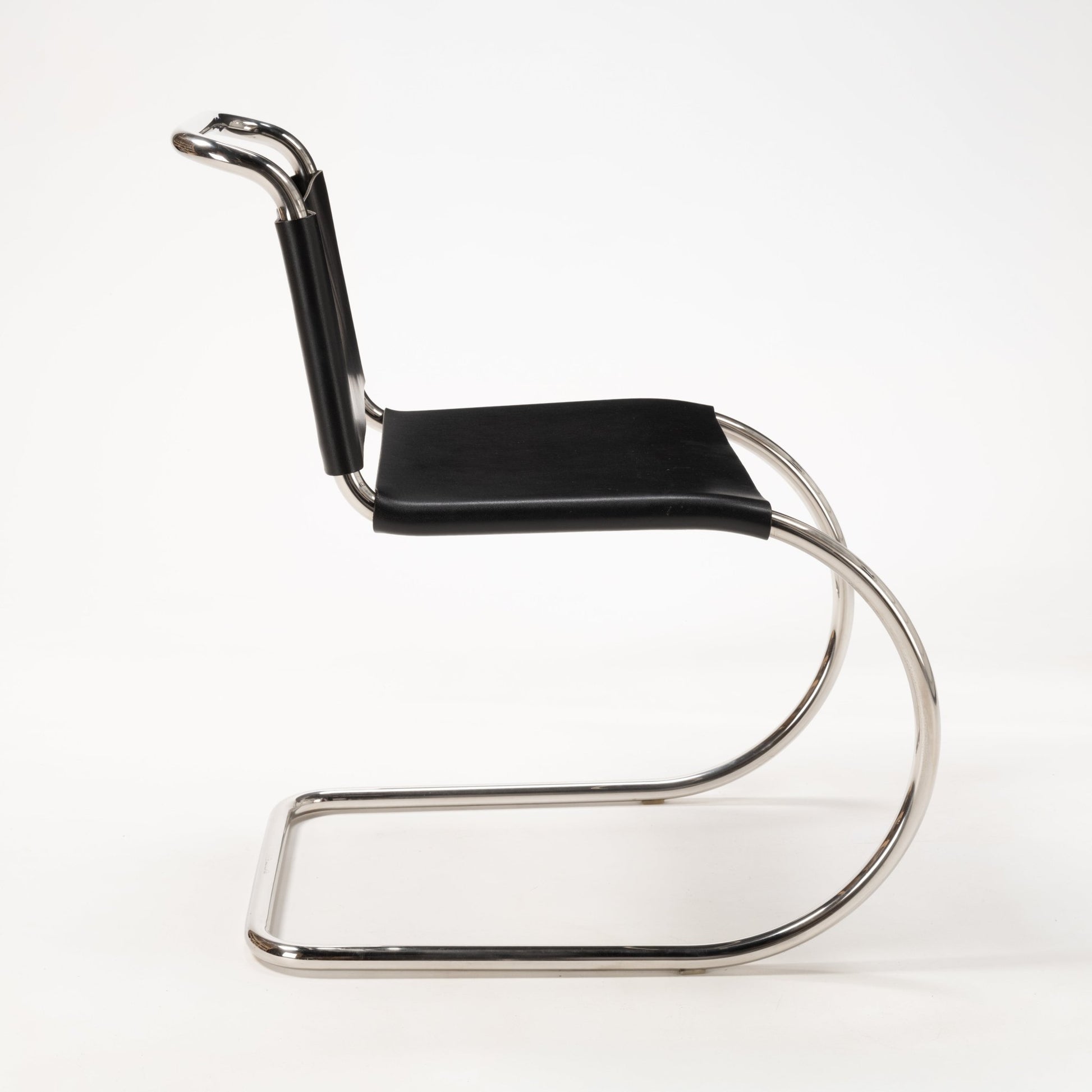 Side profile of a Van Der Rohe MR10 cantilever chair with polished chrome frame and black leather seat and backrest