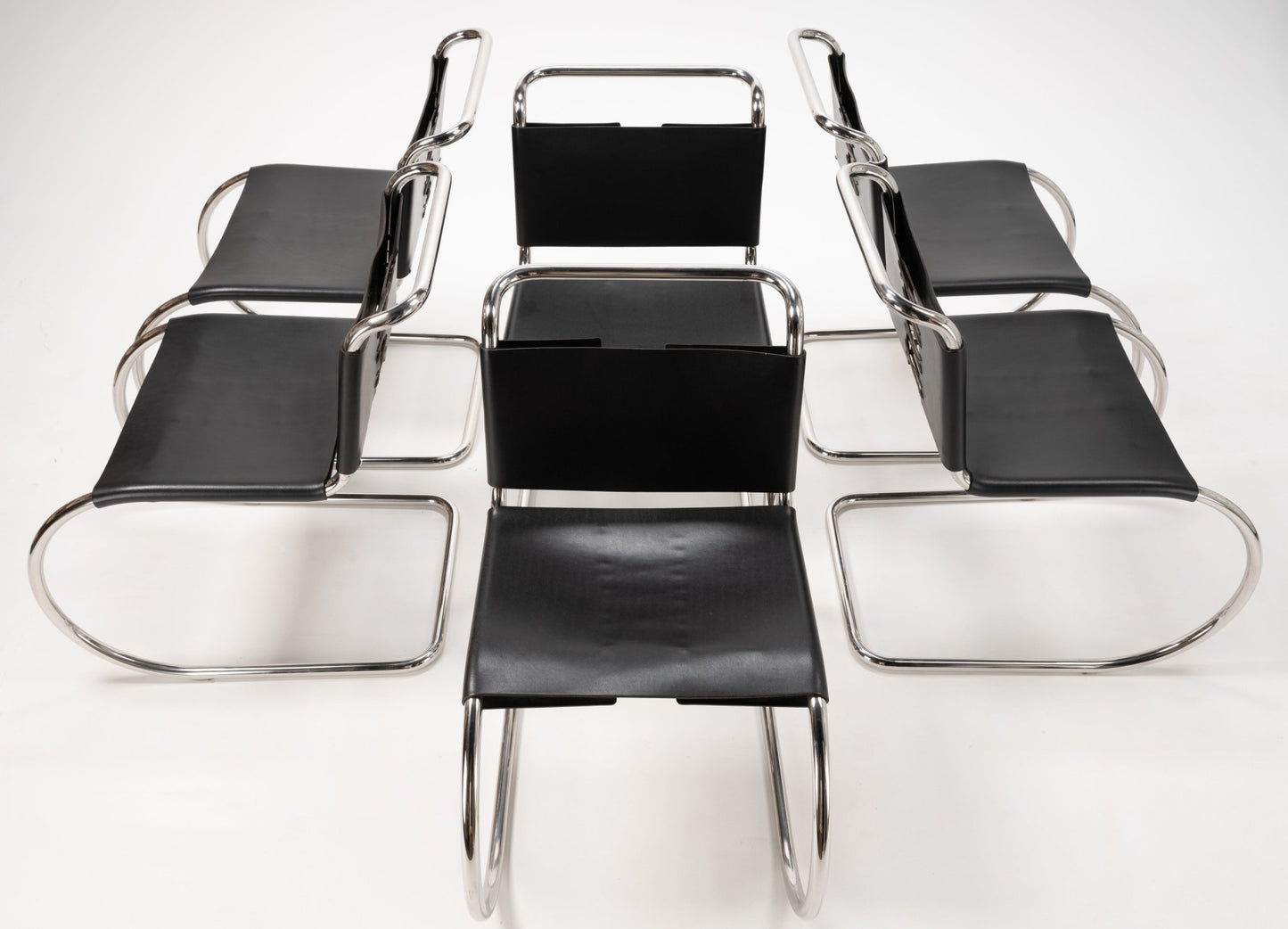Overhead view of six Van Der Rohe MR10 cantilever chairs with polished chrome frames and black leather seats and backs