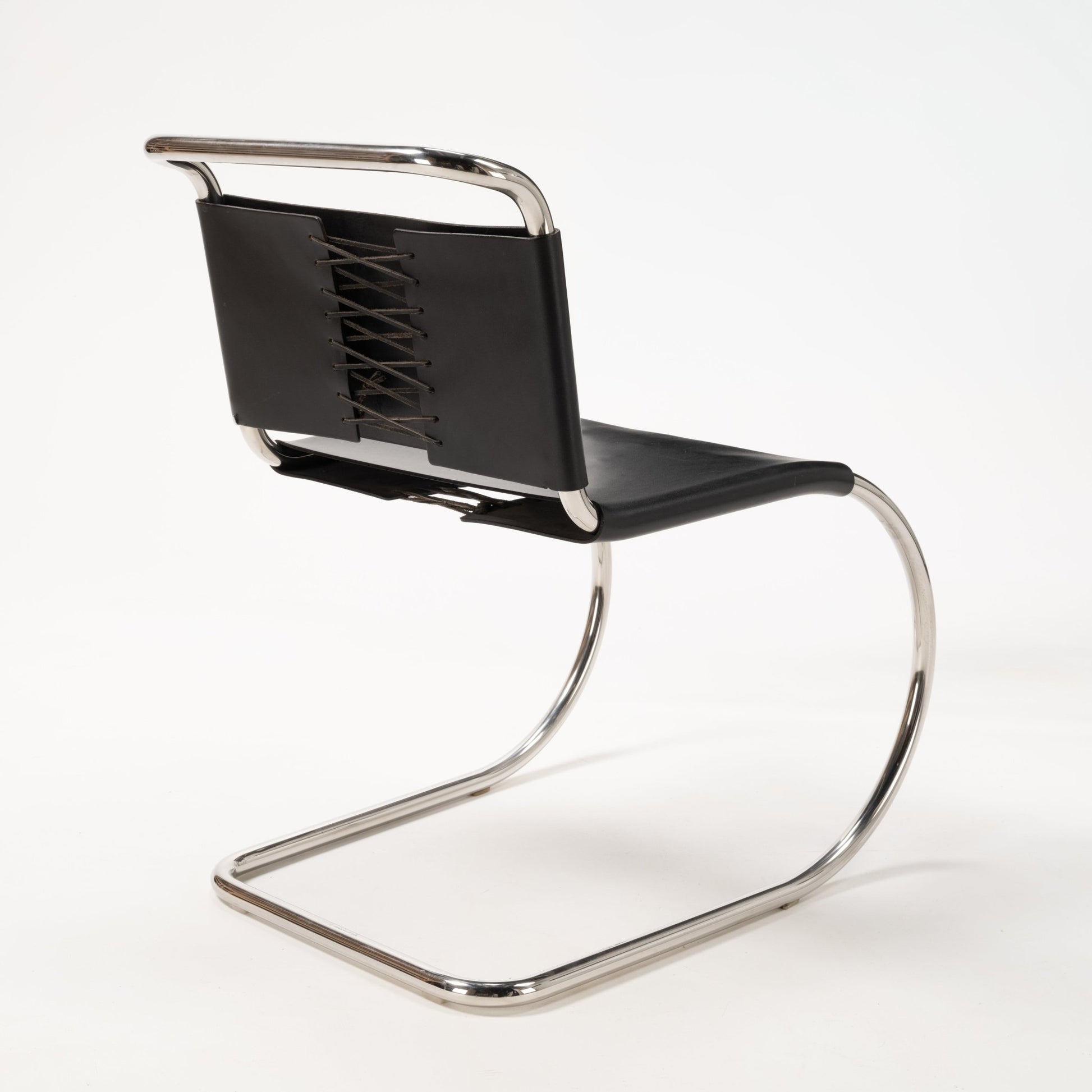 Rear view of a Van Der Rohe MR10 cantilever chair with polished chrome frame and black leather laced backrest