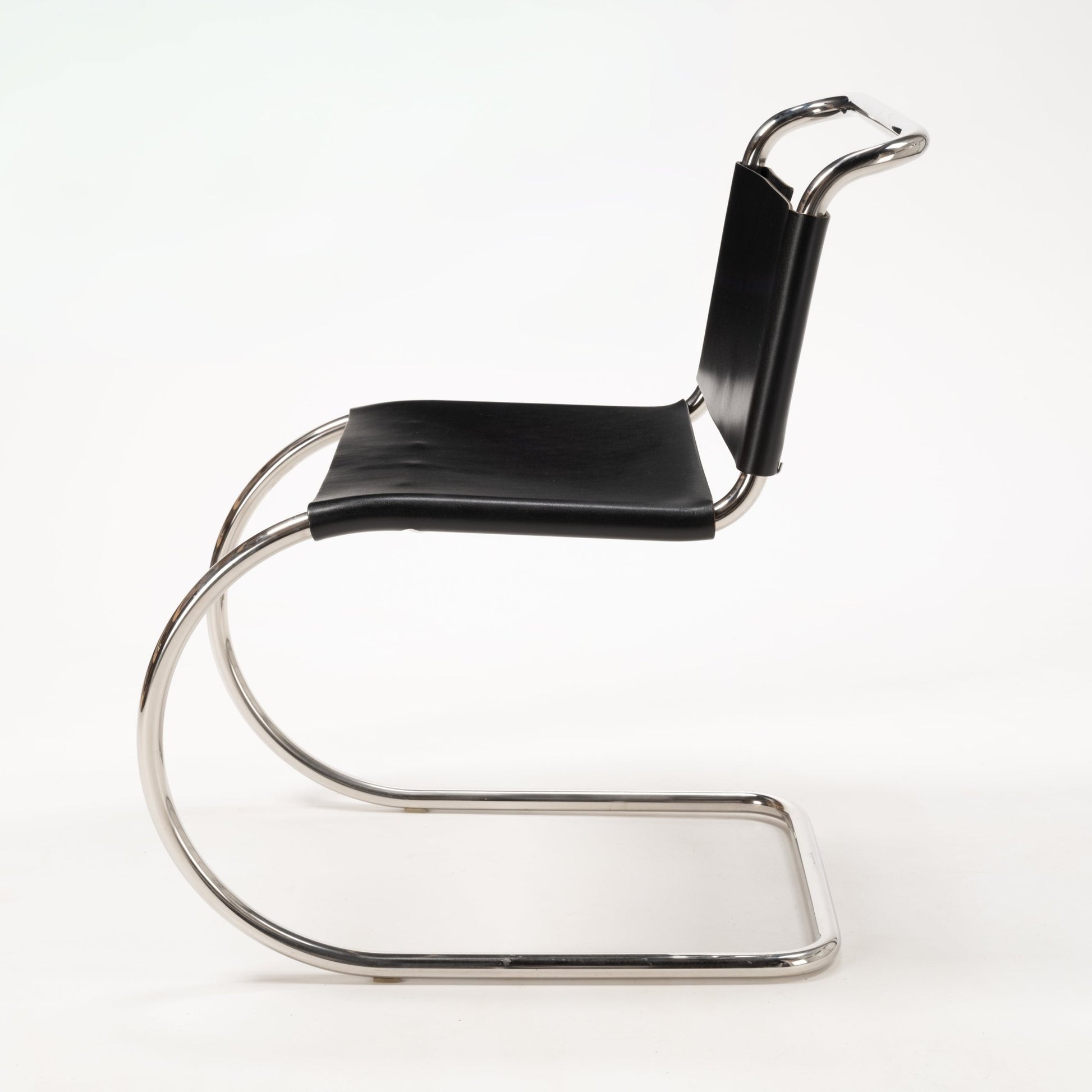 Side view of a Van Der Rohe MR10 cantilever chair with polished chrome tubular frame and black leather seat and backrest