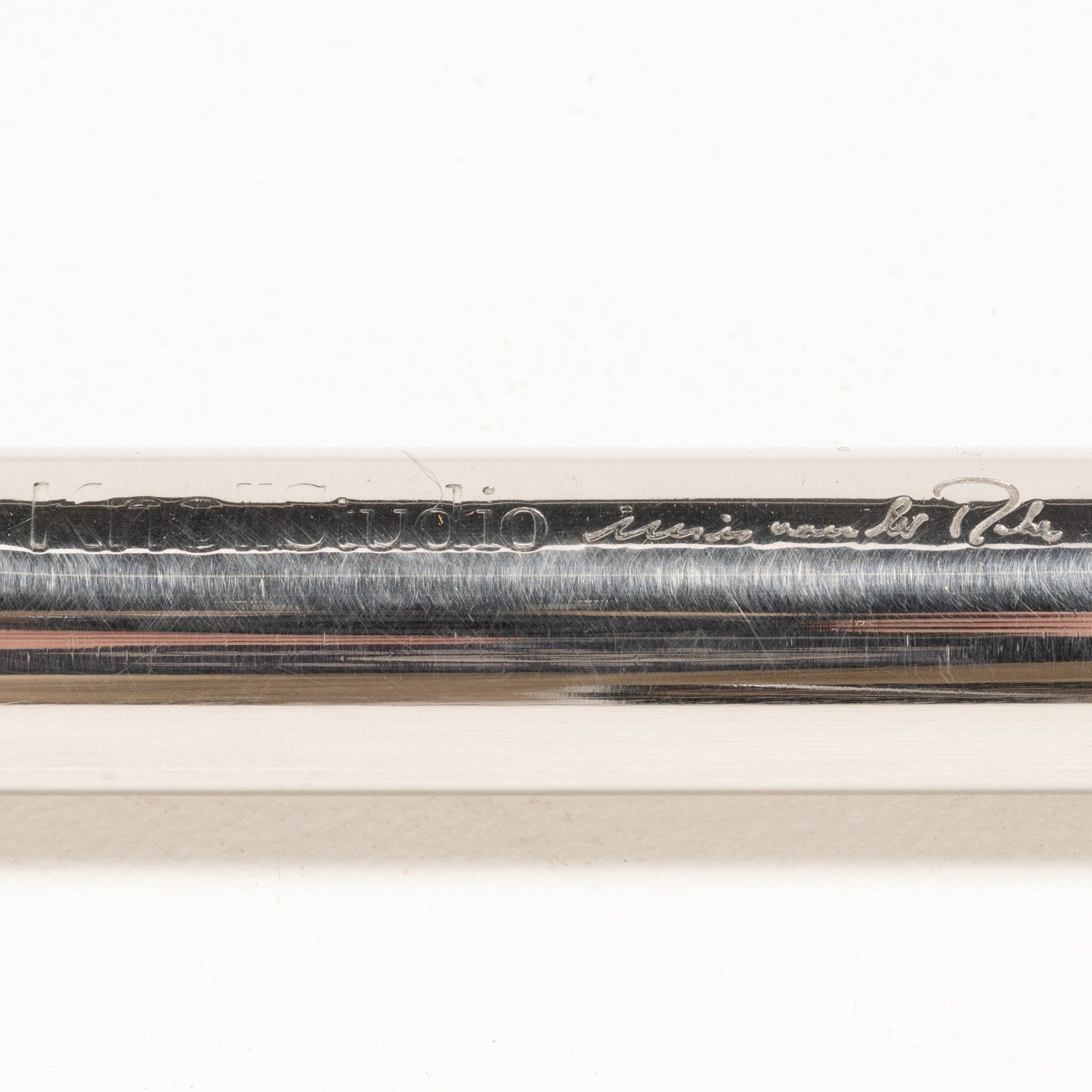 Close-up of engraved signature and branding detail on polished chrome tubular frame of Van Der Rohe MR10 chair