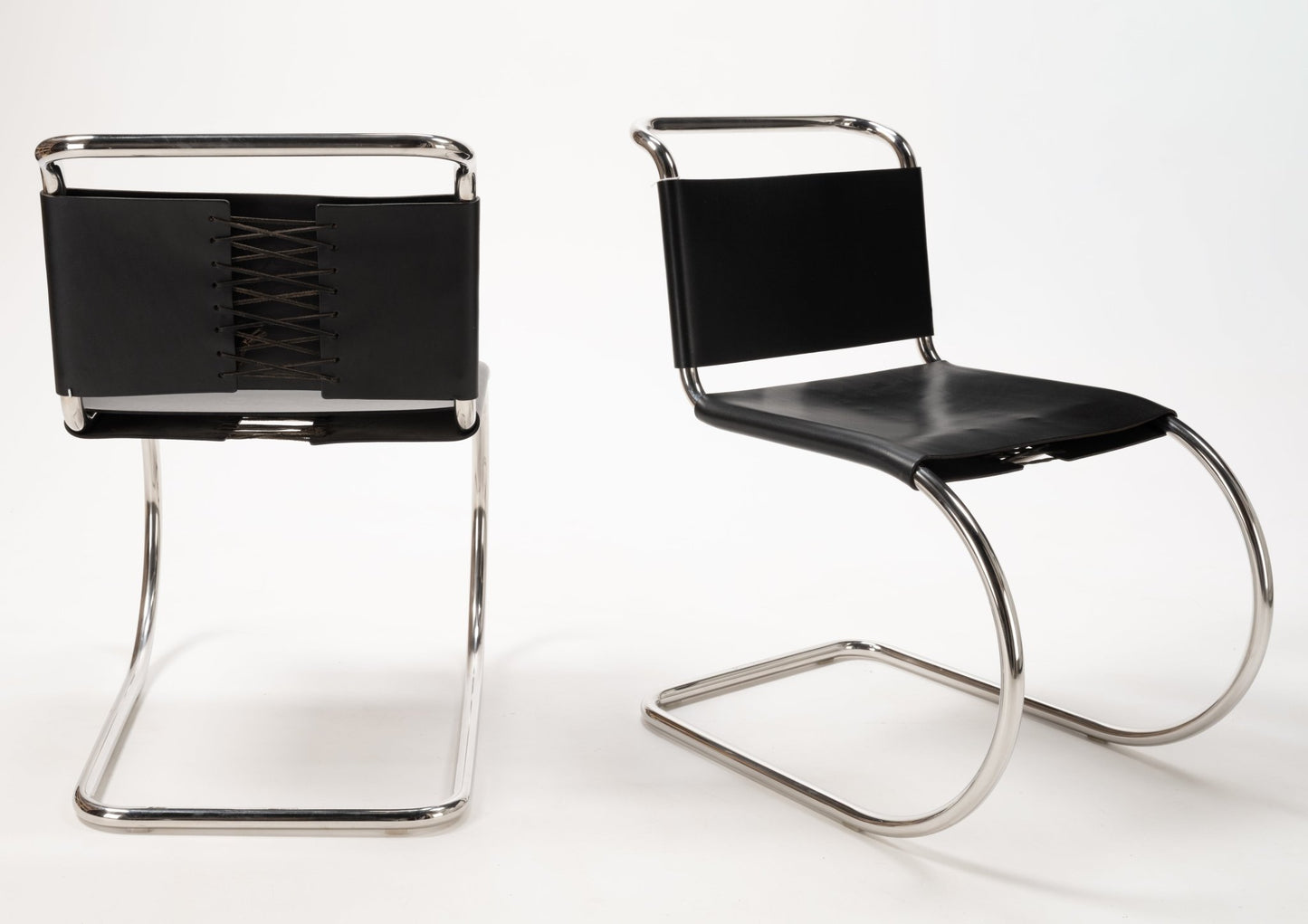 Pair of Van Der Rohe MR10 cantilever chairs with polished chrome tubular frames and black leather seats and backs