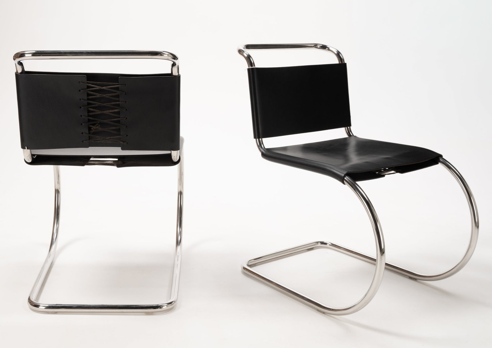 Pair of Van Der Rohe MR10 cantilever chairs with polished chrome tubular frames and black leather seats and backs