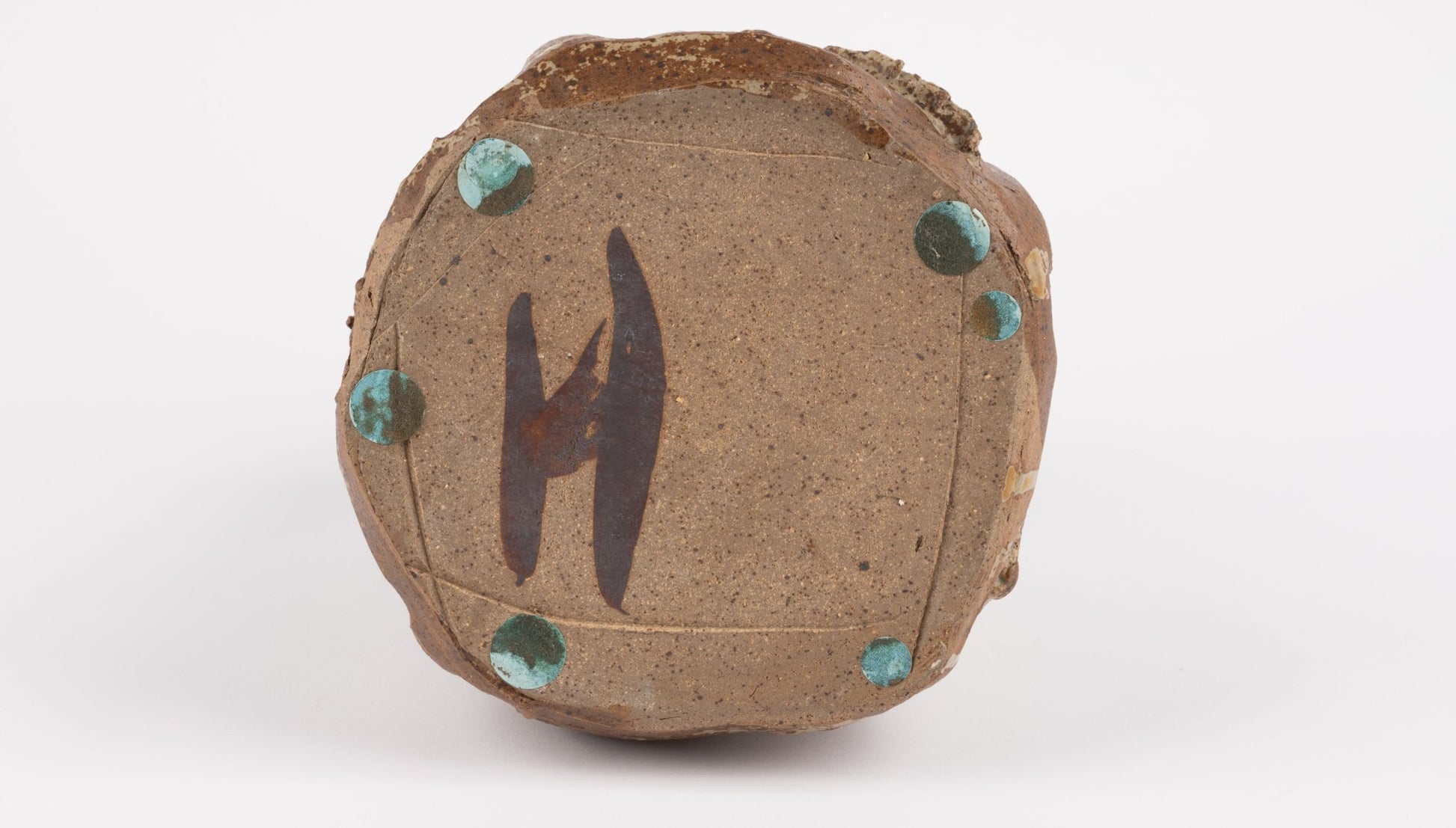 Bottom view of wabi-sabi inspired studio pottery vase with rough textured base and turquoise glaze spots