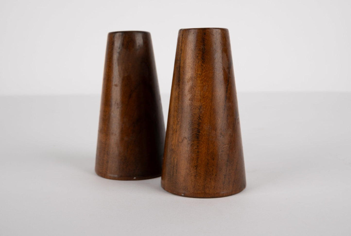 Pair of tapered solid walnut salt and pepper shakers with smooth finish inspired by Paul Evans and Phil Powell designs.