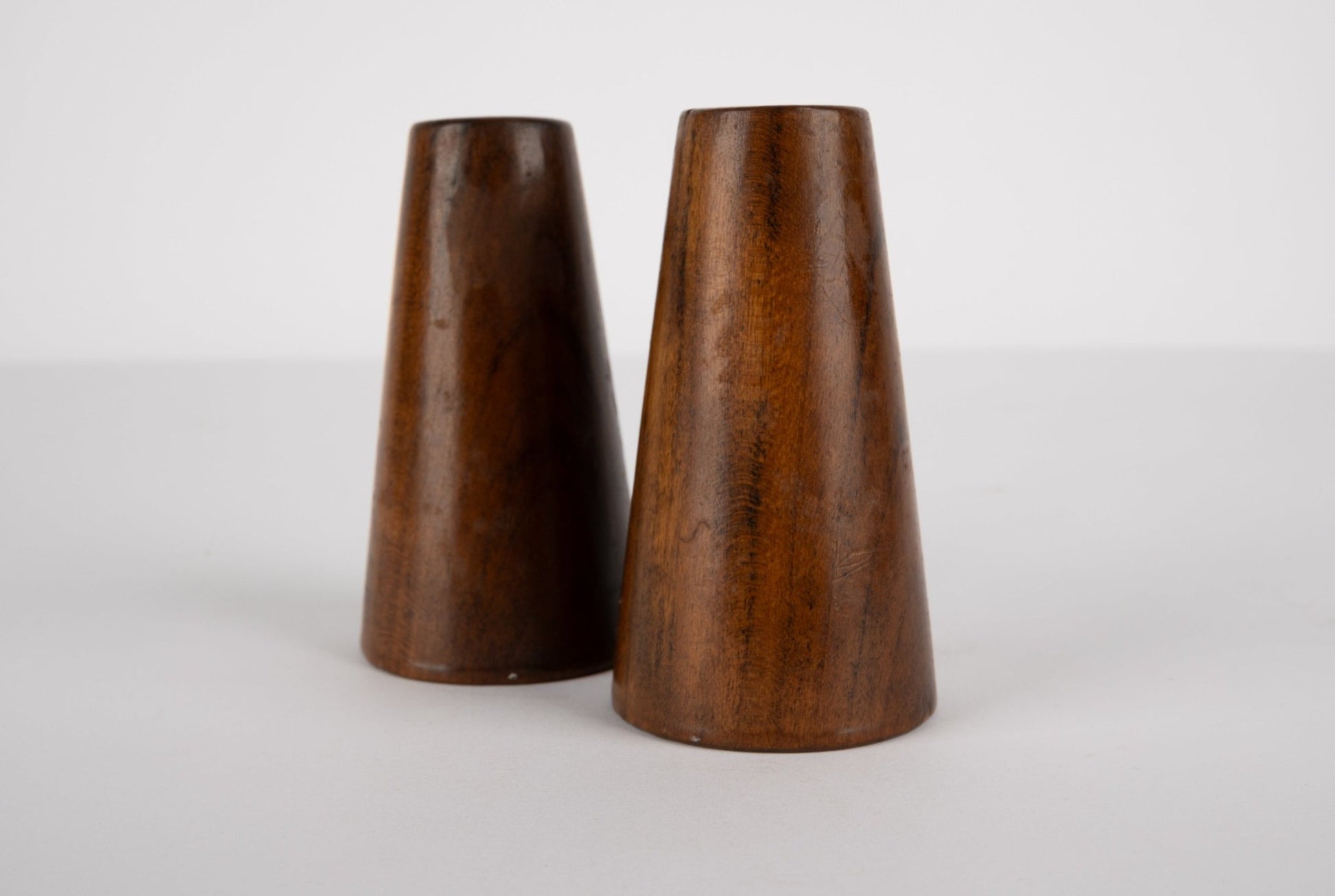 Pair of tapered solid walnut salt and pepper shakers with smooth finish inspired by Paul Evans and Phil Powell designs.