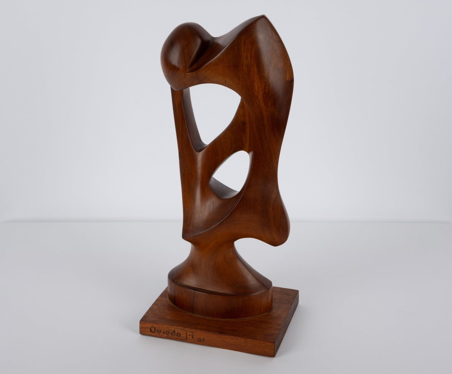 Abstract mid-century modern walnut sculpture with smooth curves and open geometric cutouts on wooden base