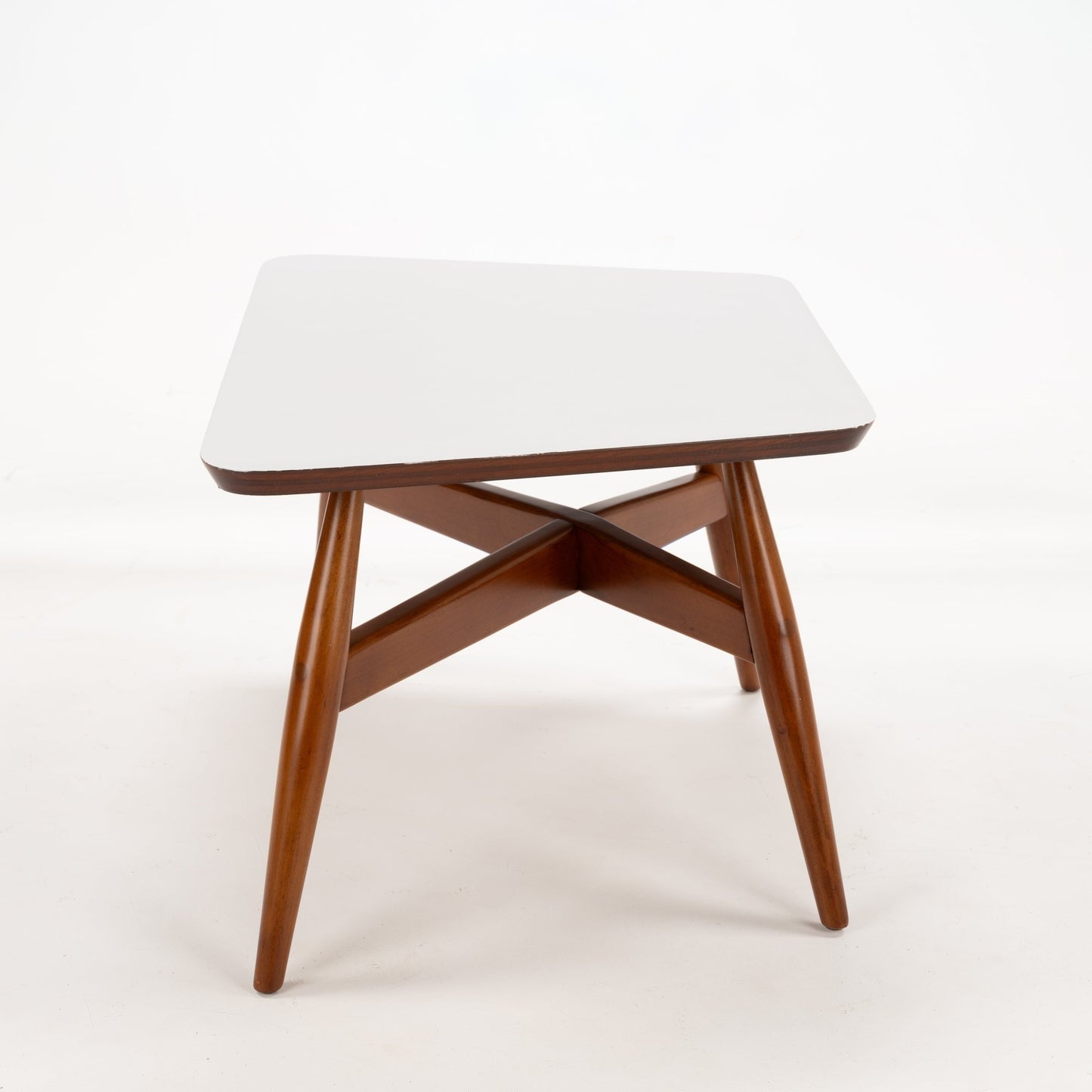 Walnut Side Table with Laminate Top featuring a smooth white surface supported by tapered walnut legs joined by a distinctive X-shaped brace, exemplifying mid century modern style.
