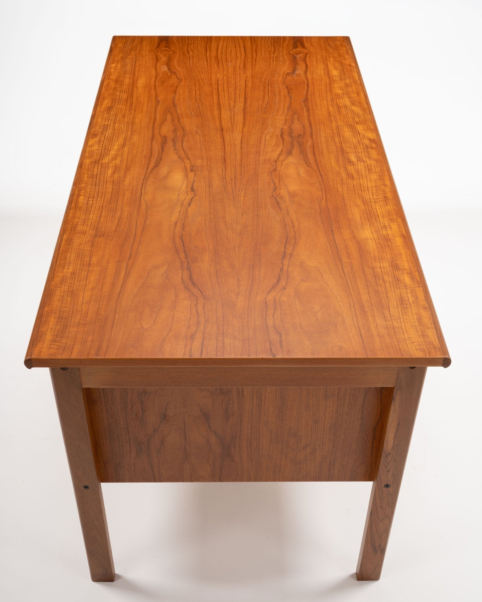 Mid-century modern teak writing desk by Peter Lovig Nielsen with smooth rectangular top and clean lines viewed from above.