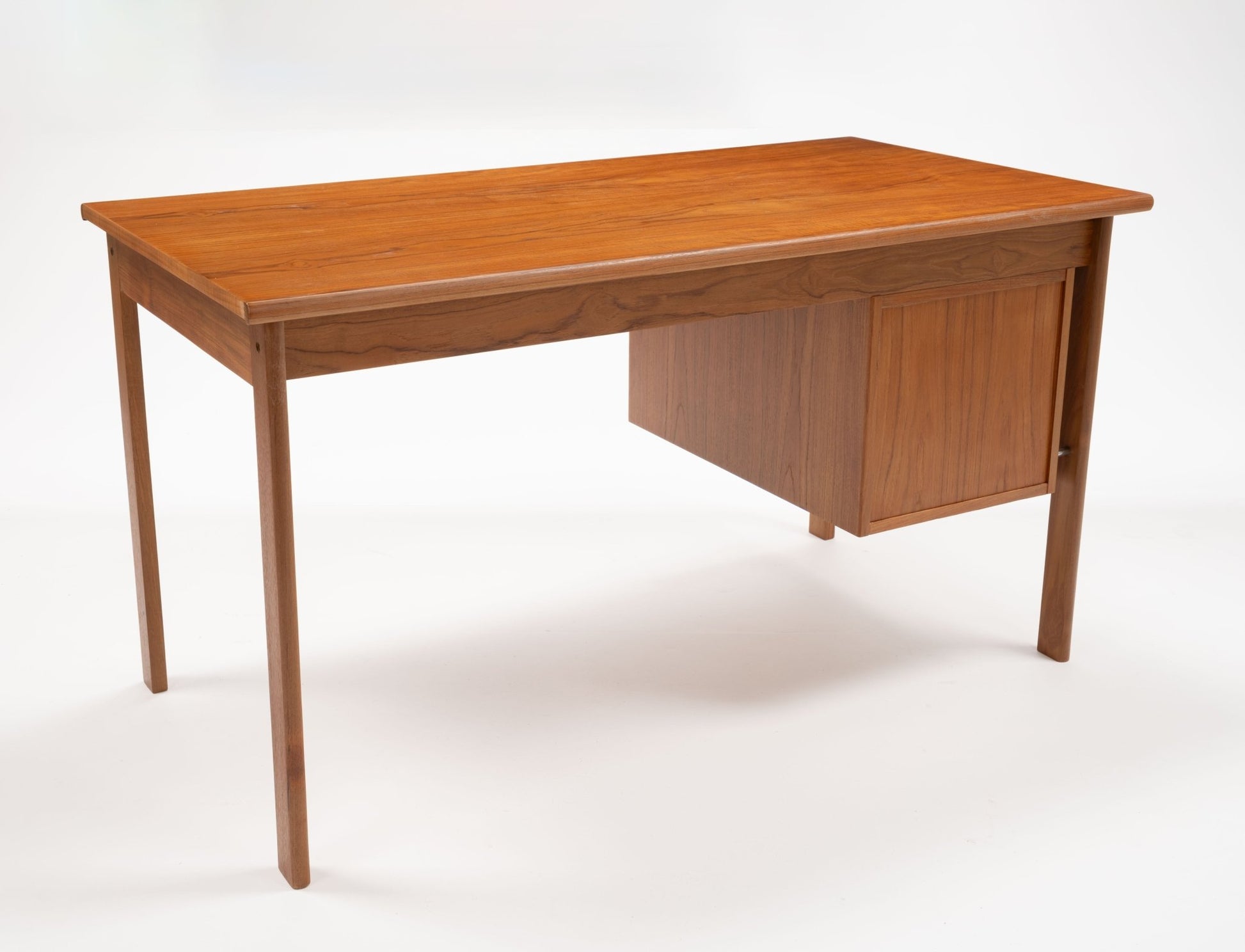 Mid-century modern teak writing desk by Peter Lovig Nielsen with sliding top and storage drawers on white background.