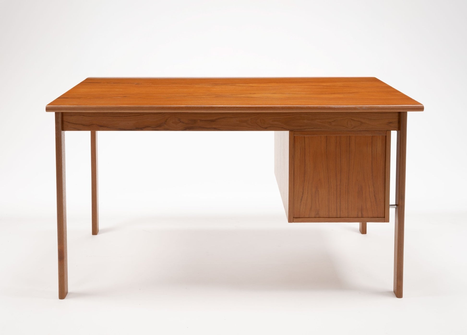 Mid-century modern teak writing desk by Peter Lovig Nielsen with sliding top and three drawers on white background.