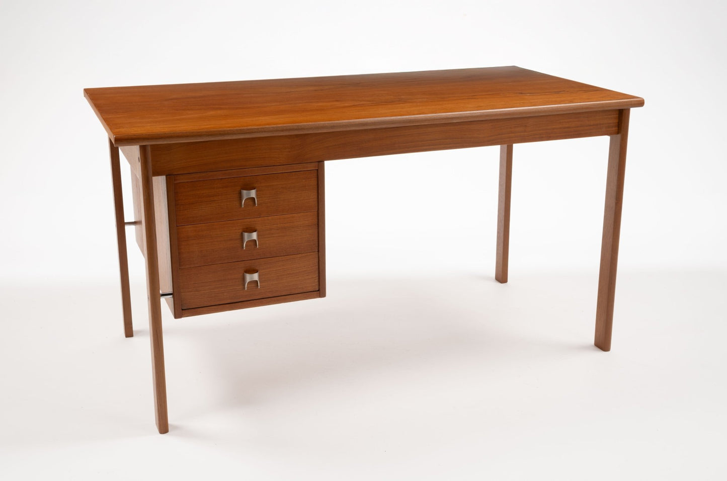 Mid-century modern teak writing desk by Peter Lovig Nielsen with sliding top and three drawers with stainless steel handles.