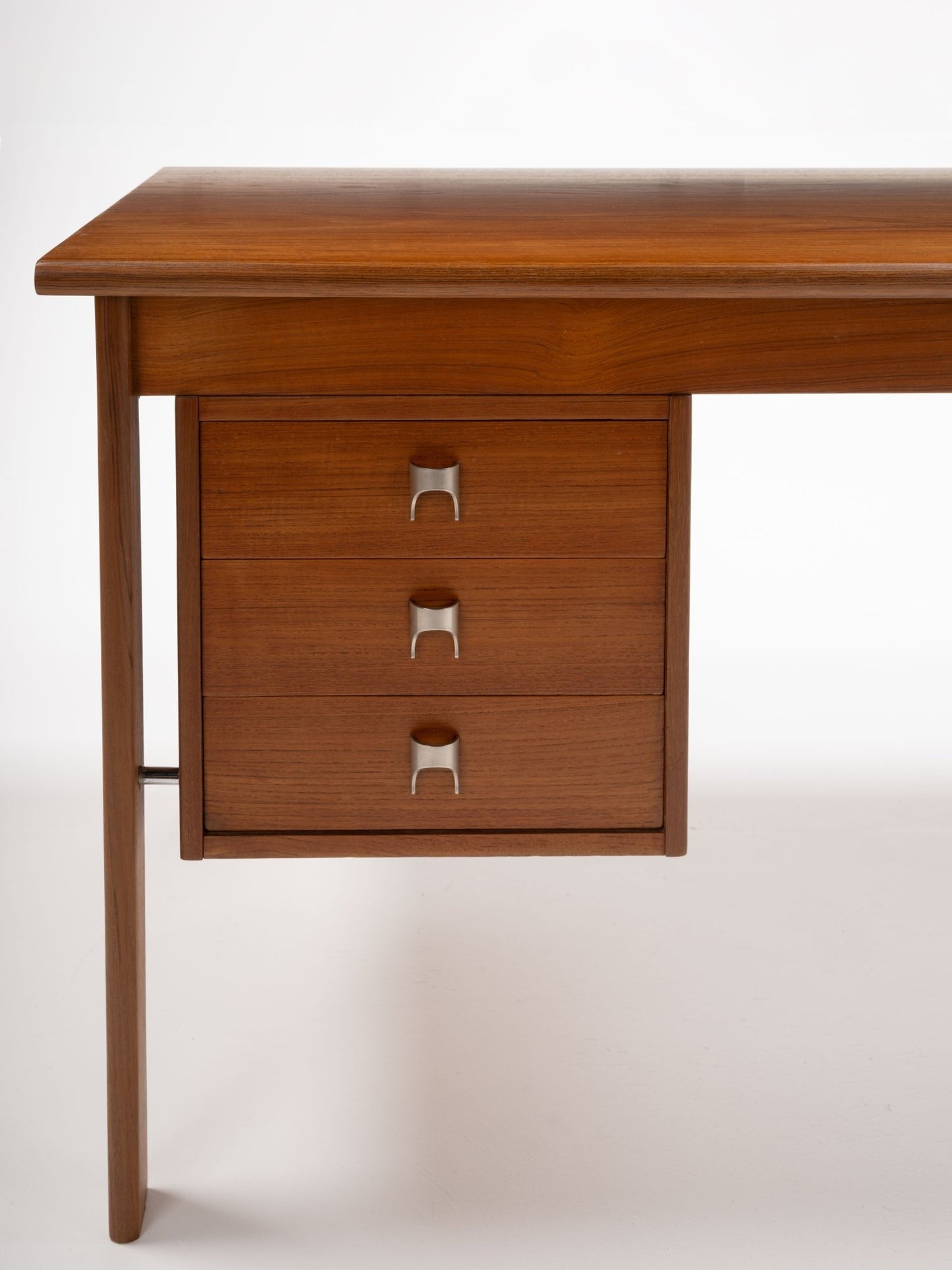 Mid-century modern teak writing desk with three drawers and sculpted stainless steel handles by Peter Lovig Nielsen.