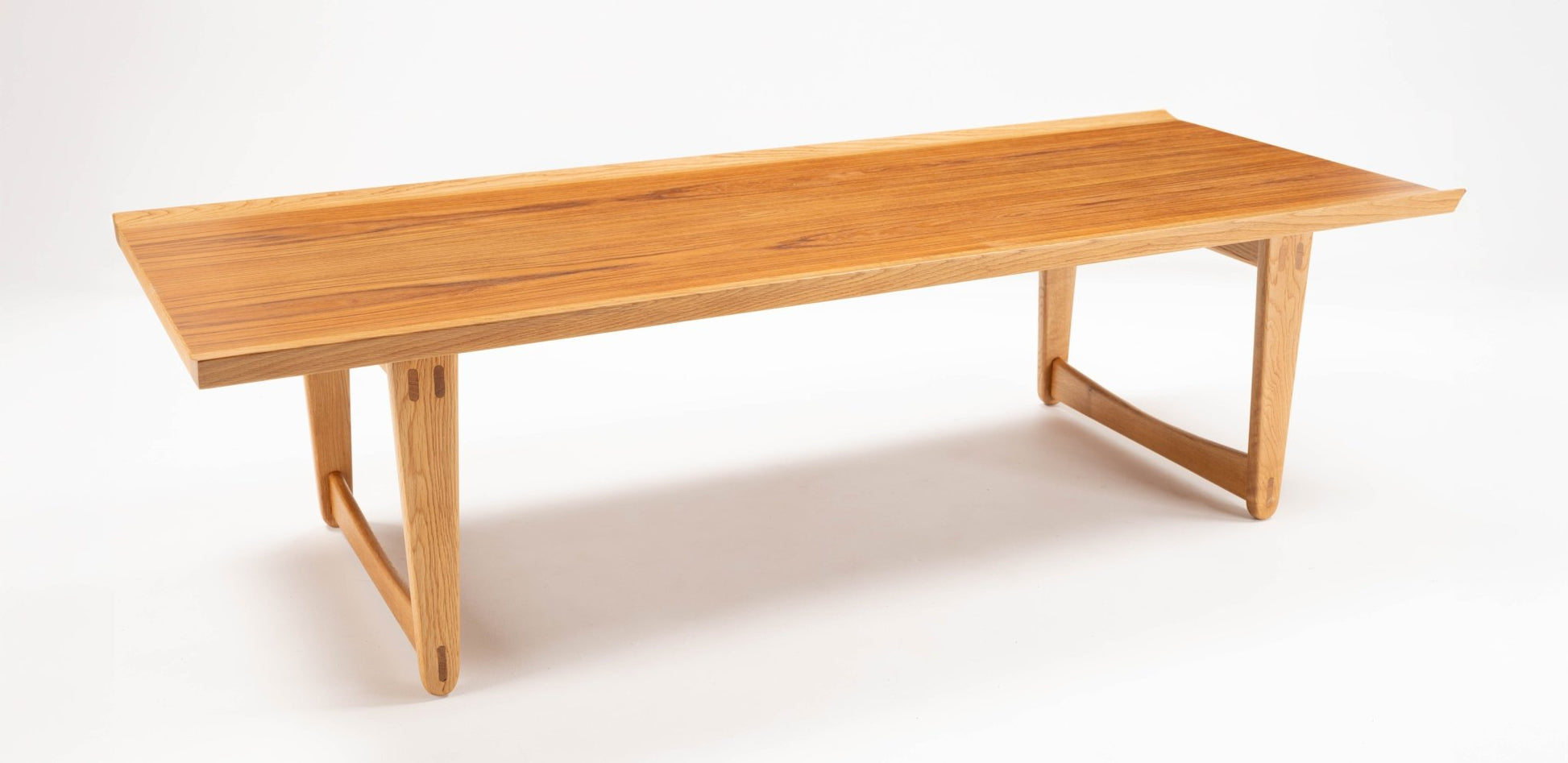 Mid-century modern Yngve Ekstrom coffee table in teak and oak with sculptural joined legs on white background.