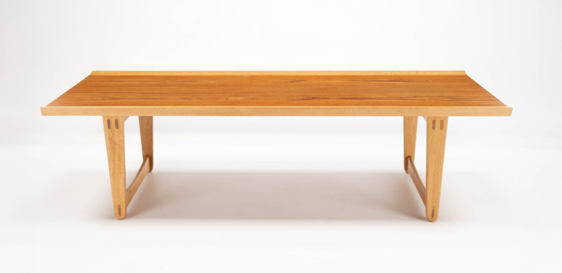 Mid-century modern Yngve Ekstrom teak and oak coffee table with clean lines and sculptural joined legs on white background