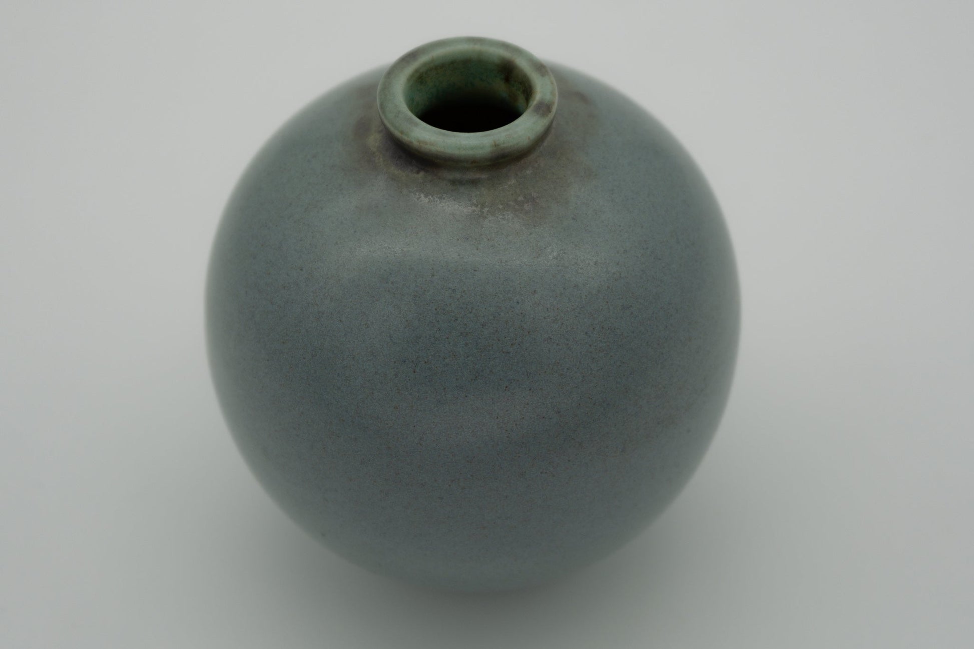 Bubble ball shaped turquoise ceramic studio pottery vase by Arthur Rushmore with fine black speckles and signed base detail.