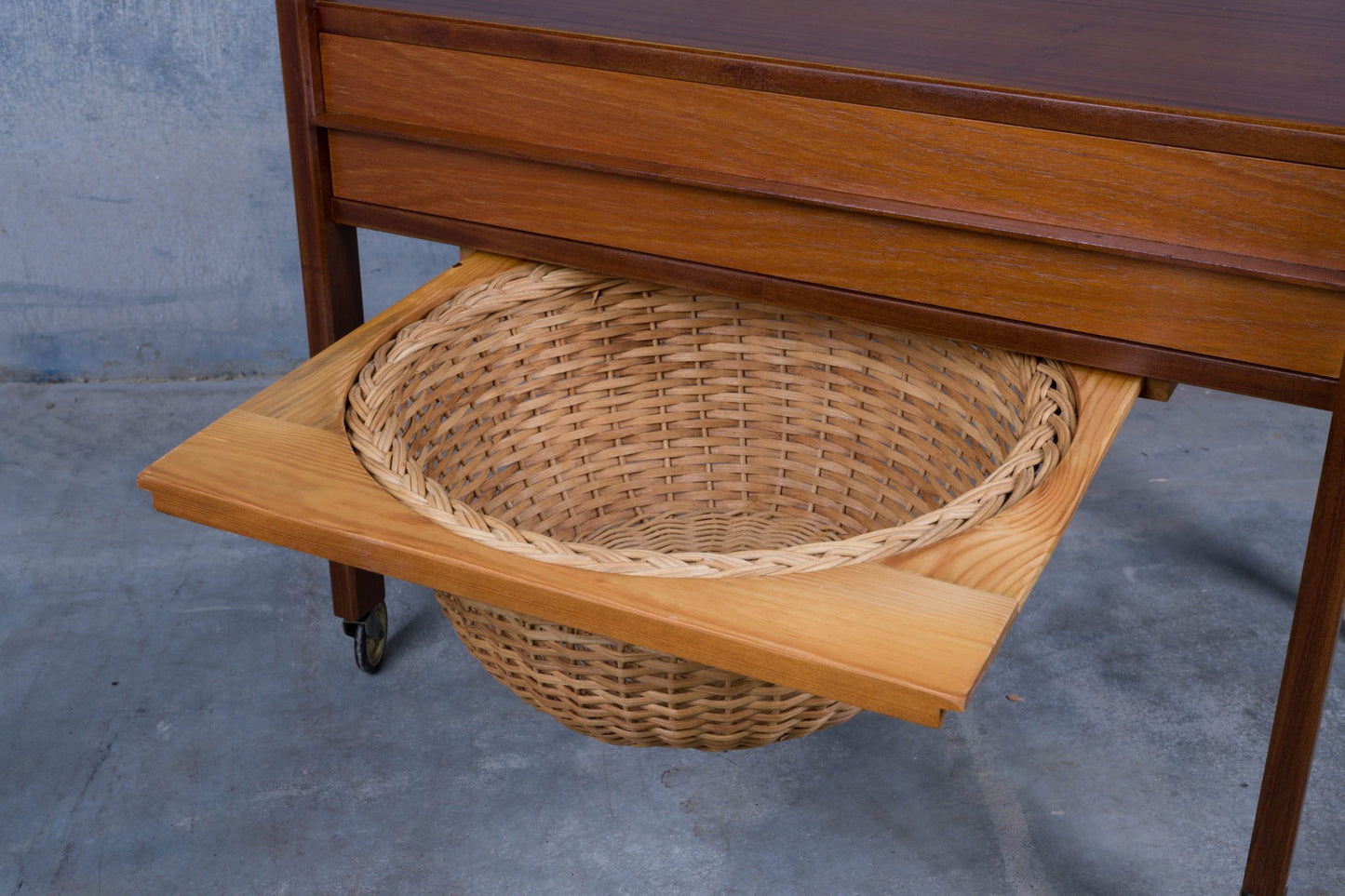 Close-up of Danish teak sewing side table showing slide-out caned circular basket and pull-out drawer details.
