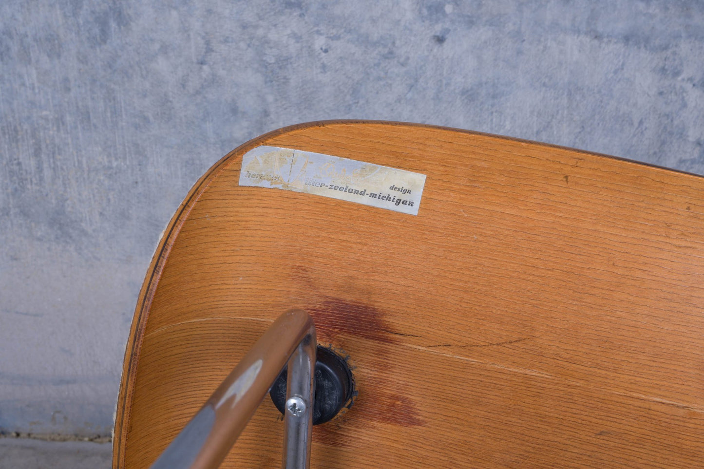 Rear view of Charles Eames lounge chair molded plywood backrest showing metal shock mount and worn label detail