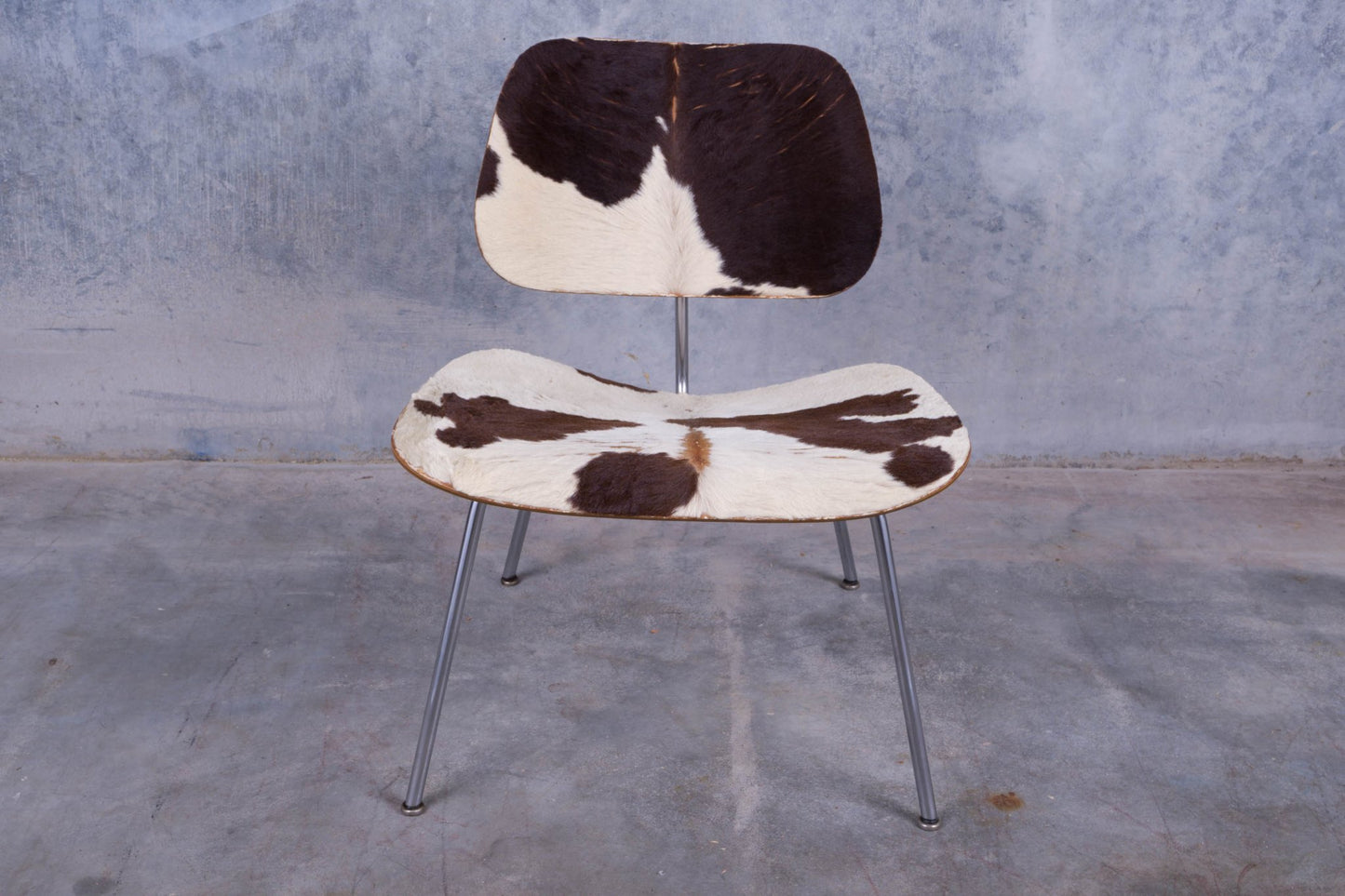 Front view of Charles Eames lounge chair with molded plywood frame and black and white cowhide upholstery