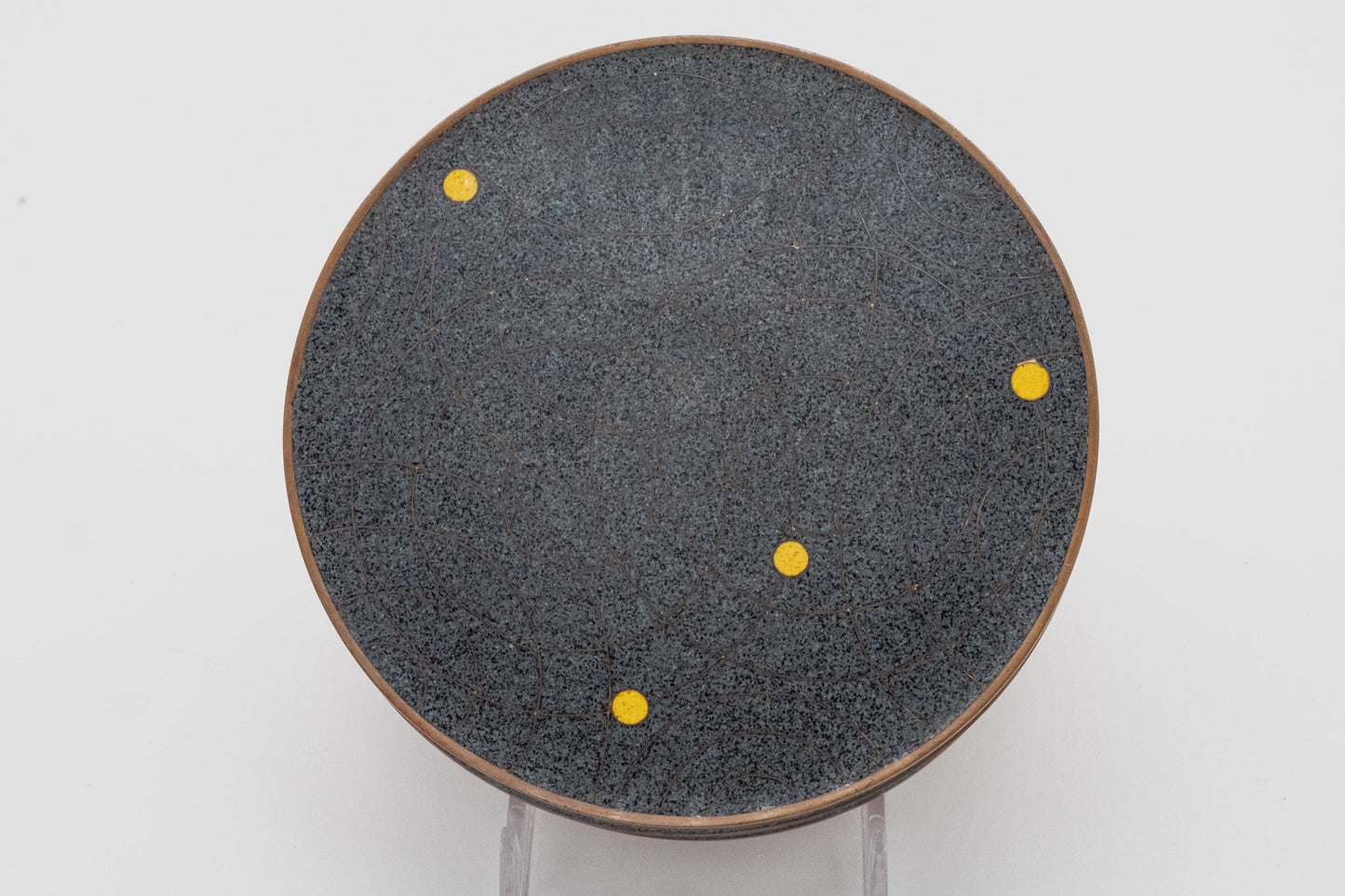 Top view of Fabienne Jouvin copper canister with black and gray speckled surface, bronze rim, and yellow dot pattern