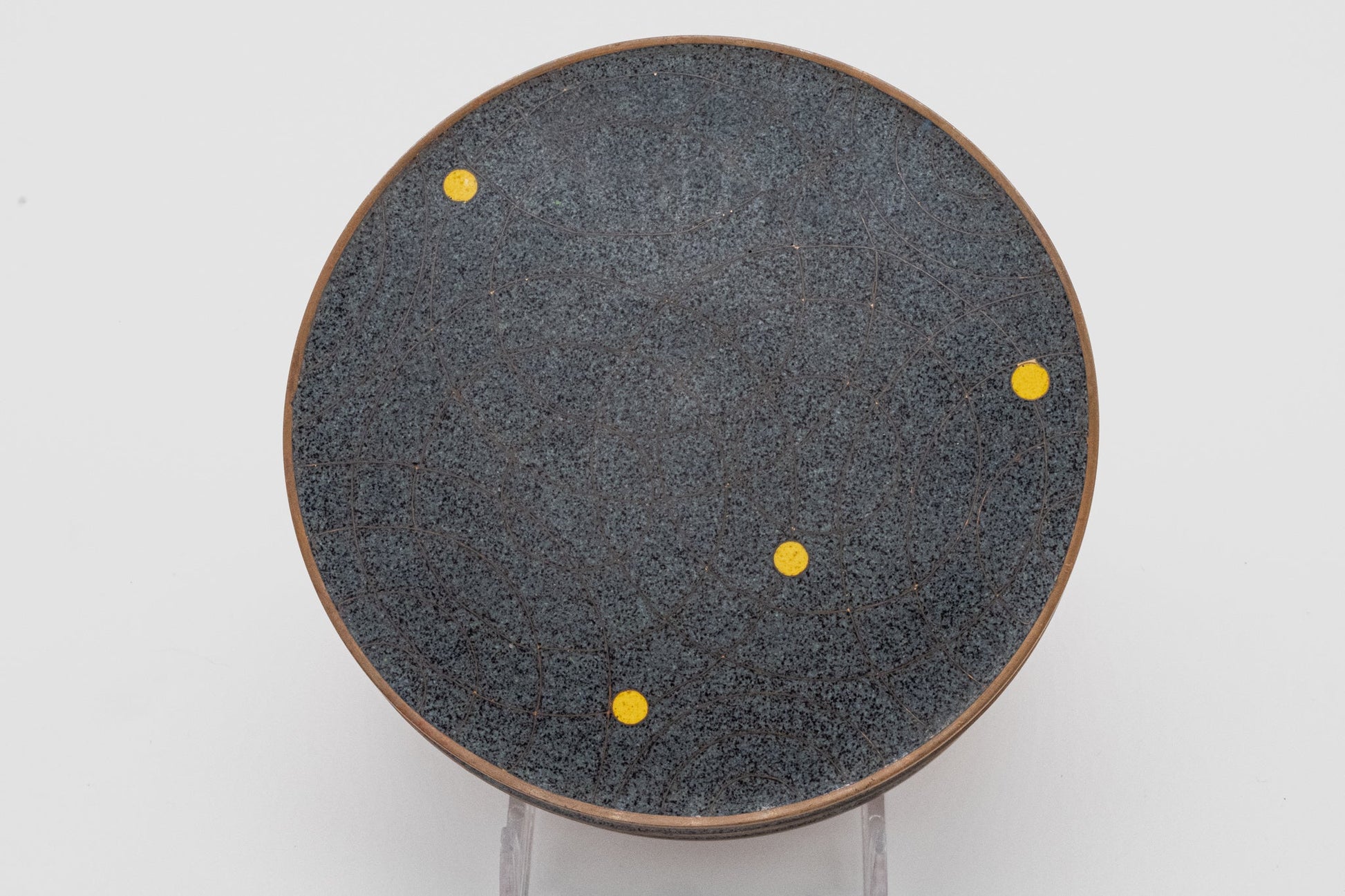 Top view of Fabienne Jouvin copper canister with black and gray speckled surface, bronze rim, and yellow dot pattern