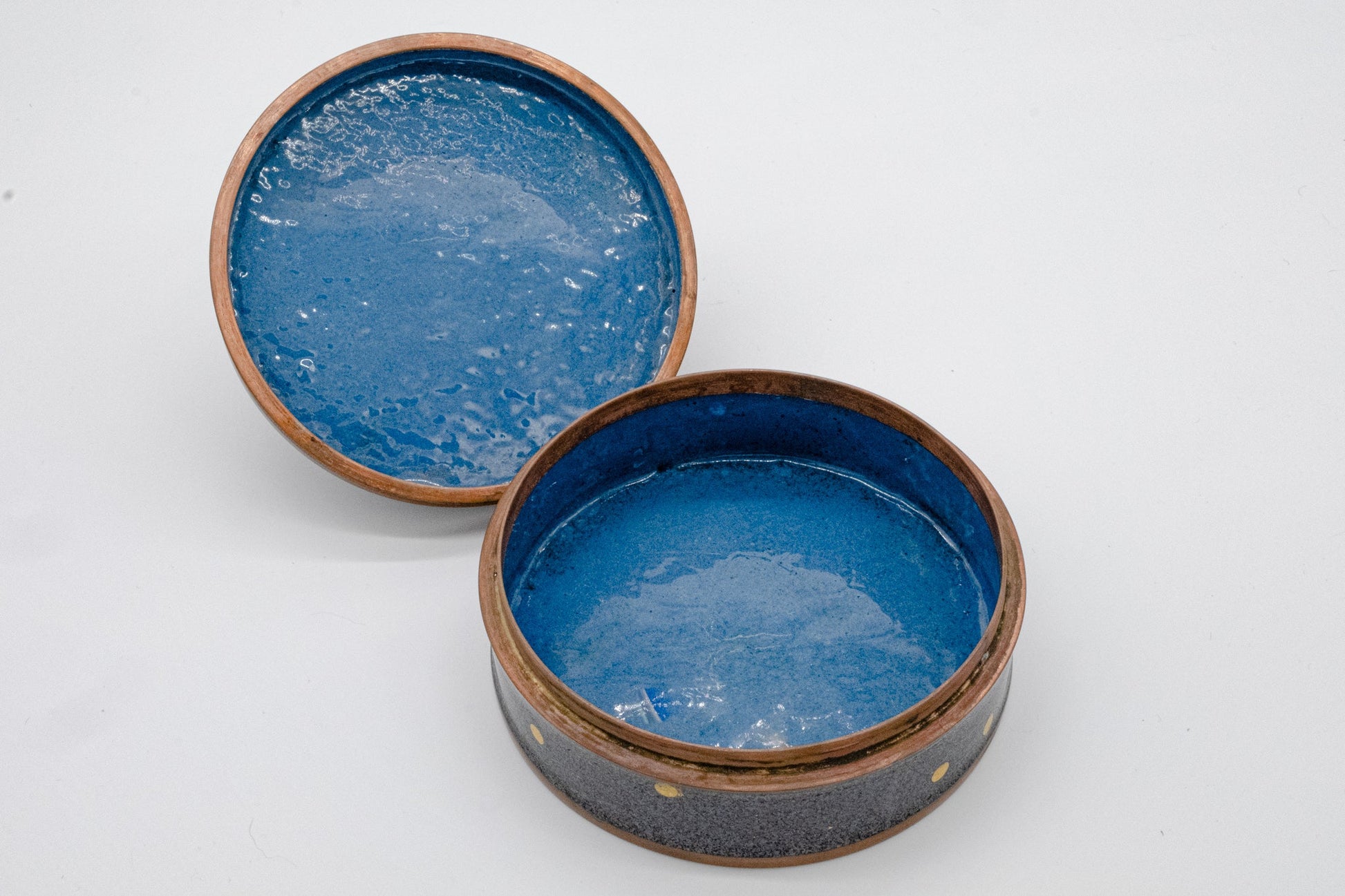 Open round ceramic canister with textured blue interior and speckled gray exterior with brown rim accents