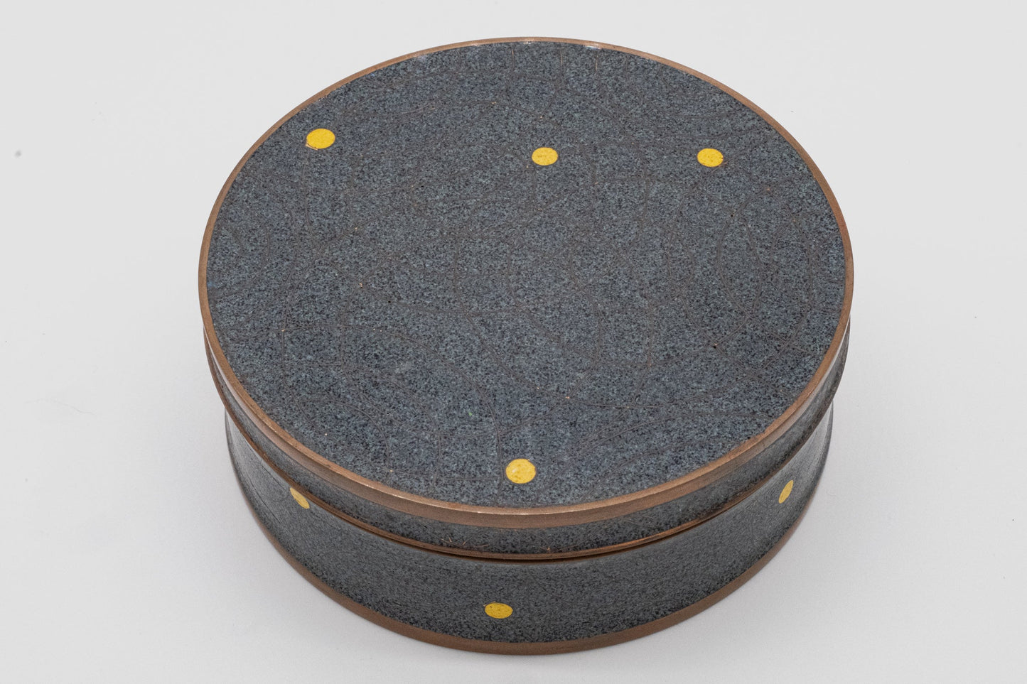 Round Fabienne Jouvin copper canister with black and gray speckled surface, yellow dots, and bronze rim accents.