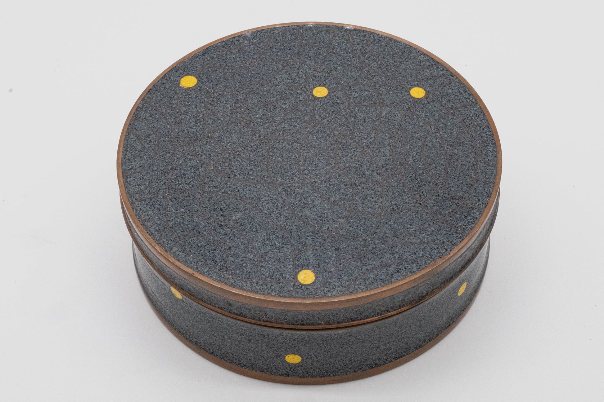 Round Fabienne Jouvin copper canister with black and gray speckled surface, yellow dots, and bronze rim accents.