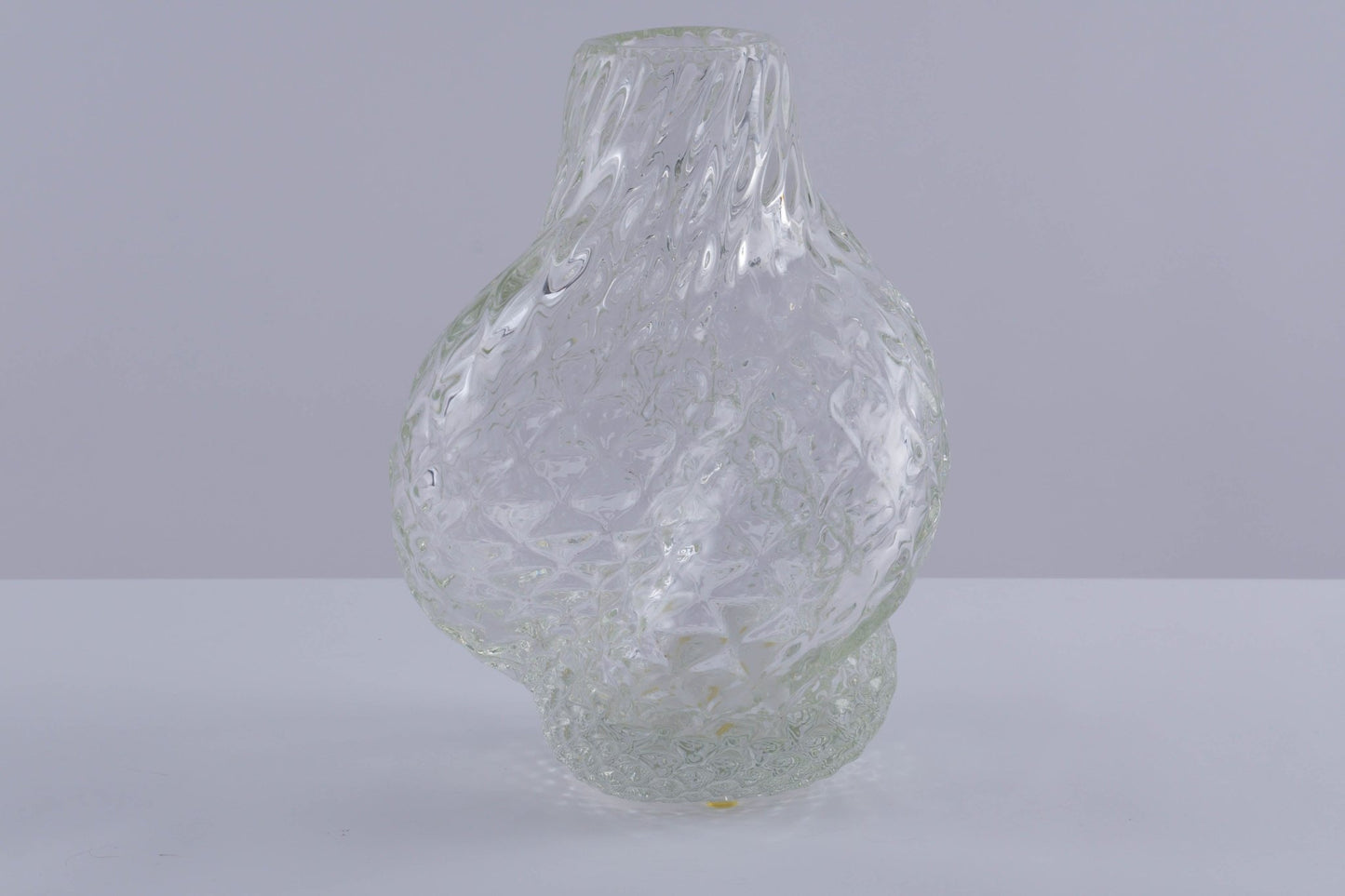 Asymmetrical Flavio Poli glass vessel with textured spiral design and clear finish on plain background.