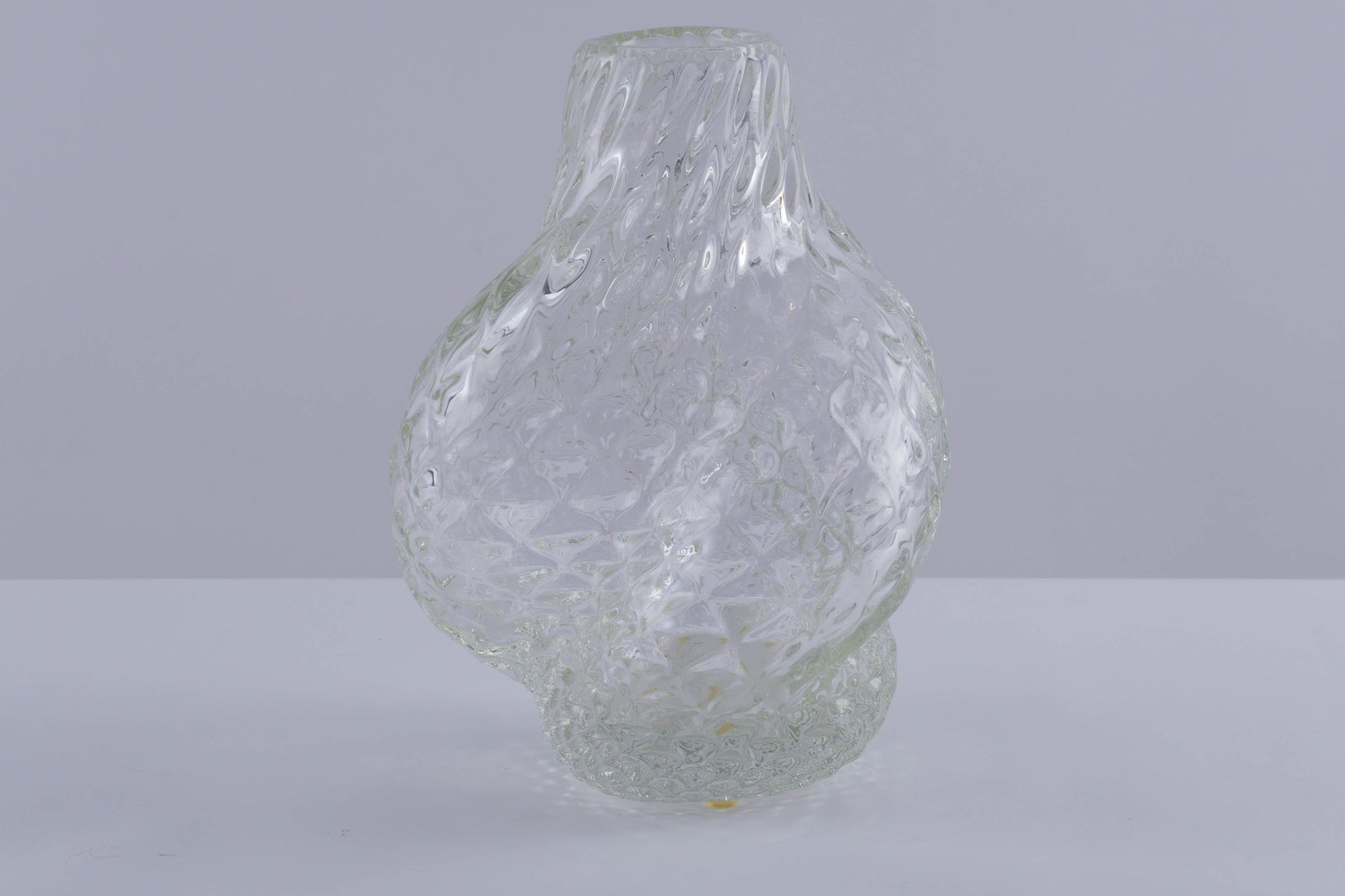 Asymmetrical Flavio Poli glass vessel with textured spiral design and clear finish on plain background.