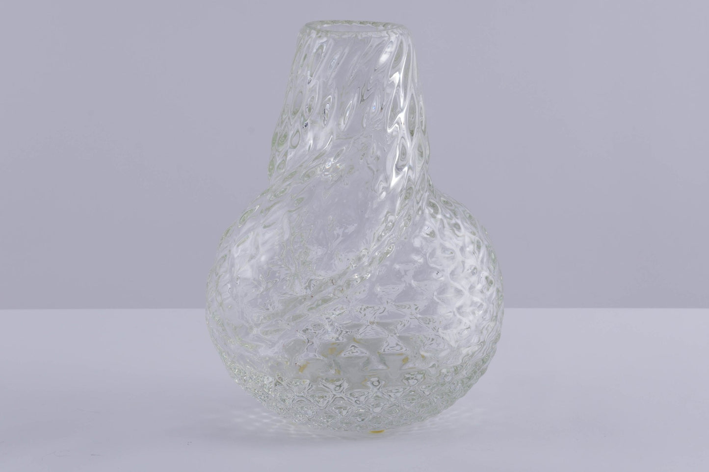 Asymmetrical spiral glass vessel with textured surface, designed by Flavio Poli, on neutral background.
