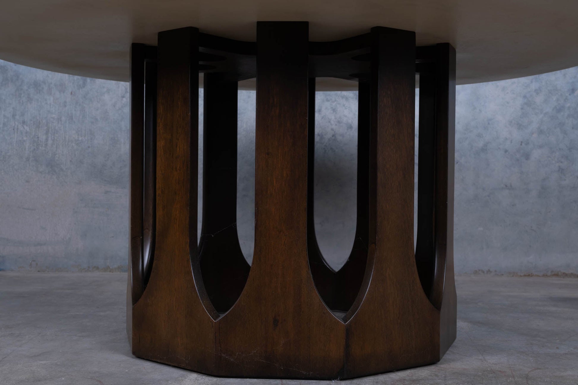 Carved circular mahogany base supporting a 1960s Harvey Probber travertine coffee table with spiral inlaid top.