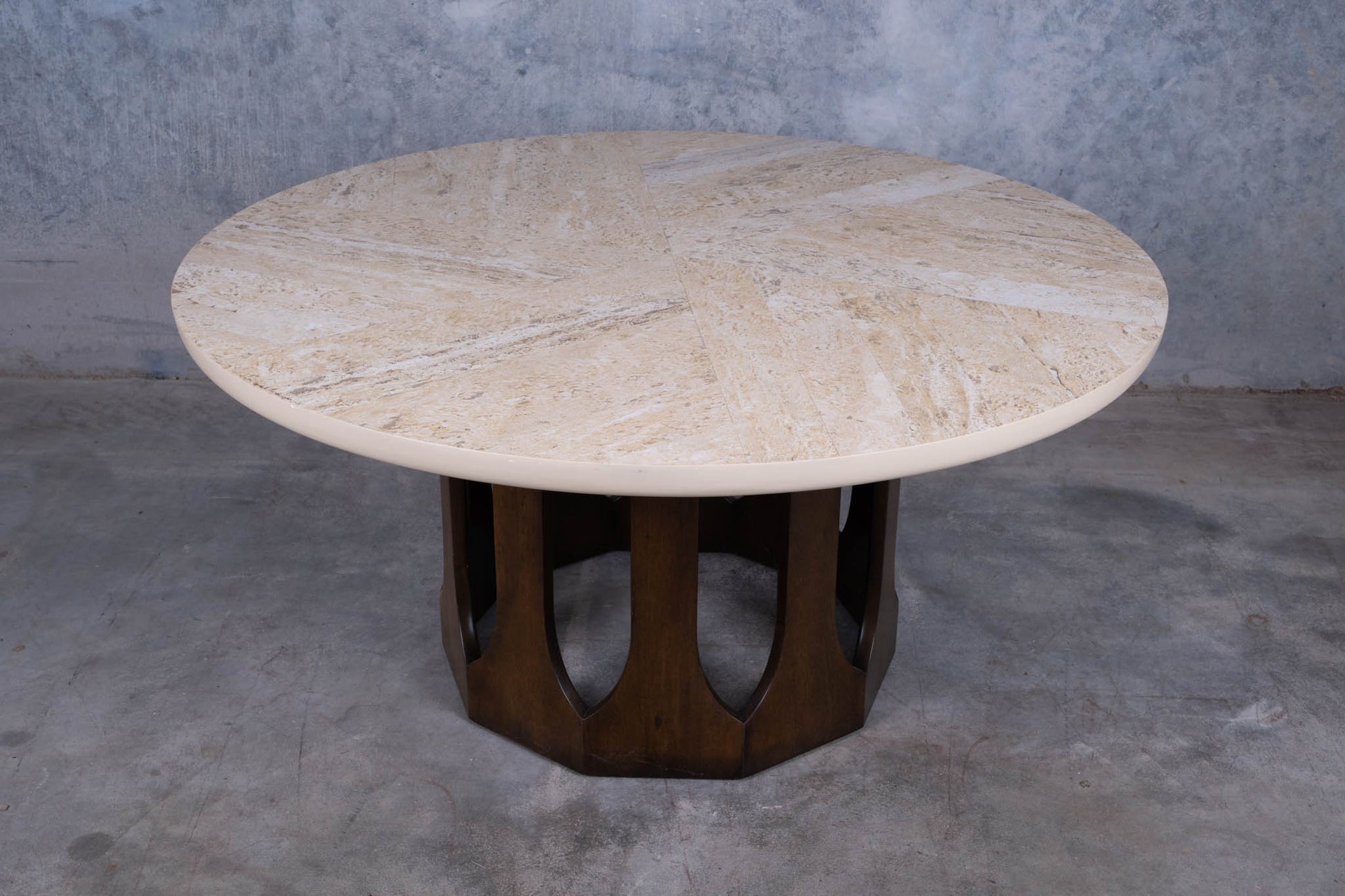 1960s circular travertine coffee table with spiral pattern top and carved mahogany arcade base on concrete floor