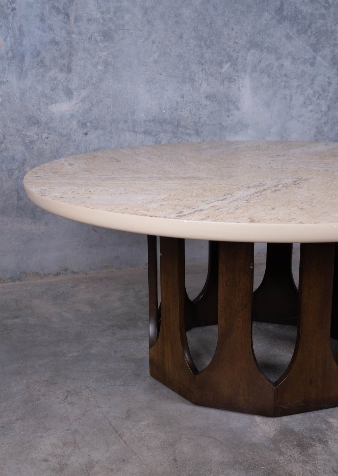 1960s circular travertine coffee table with spiral pattern top and carved mahogany arcade base on concrete floor
