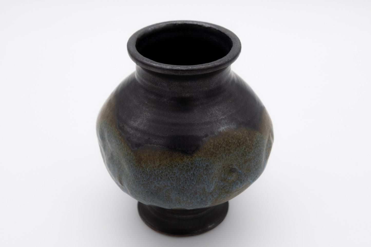 Spherical studio pottery vase with indented body and multi-colored glaze, signed on the bottom, photographed on white background