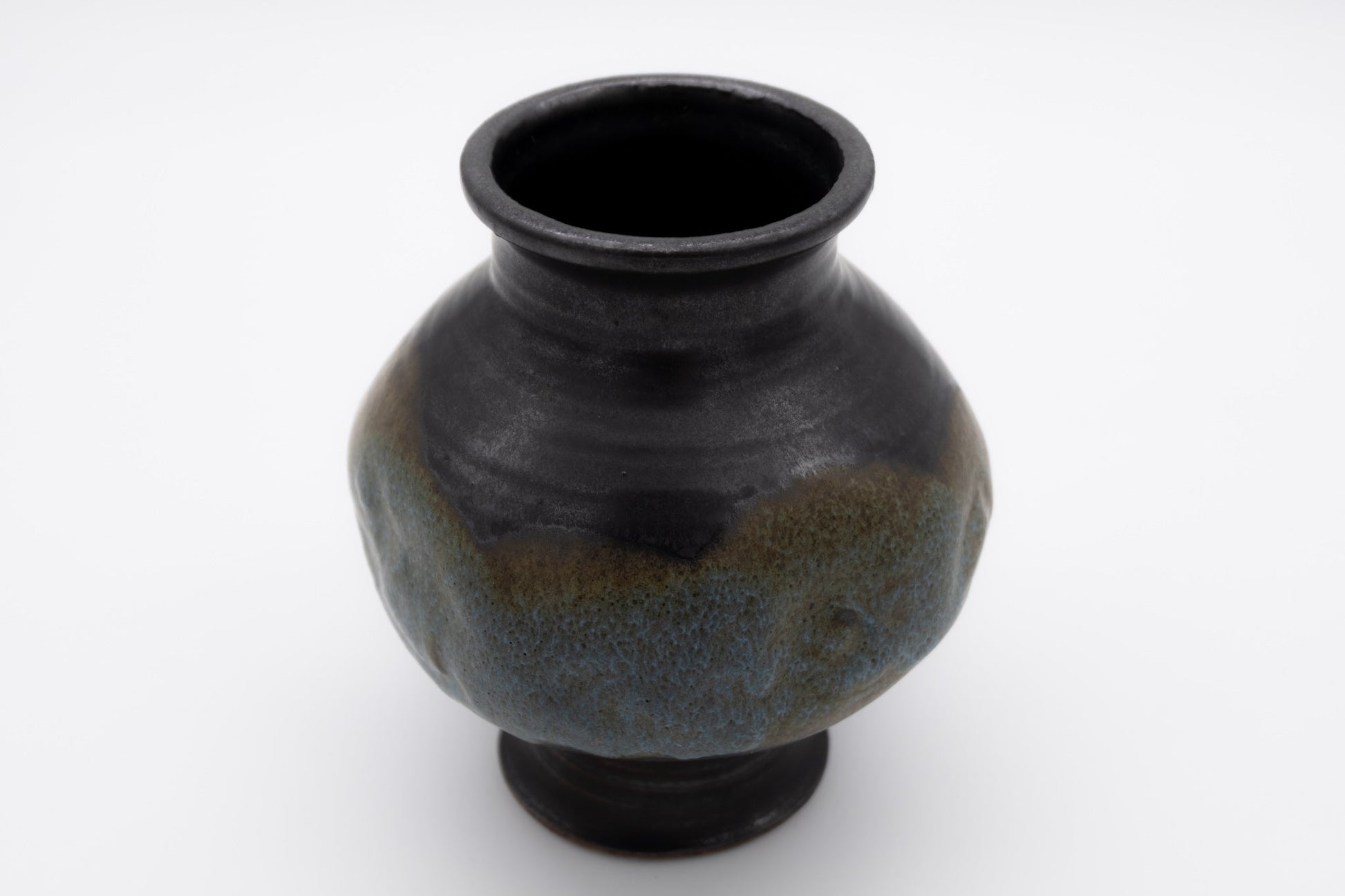 Spherical studio pottery vase with indented body and multi-colored glaze, signed on the bottom, photographed on white background