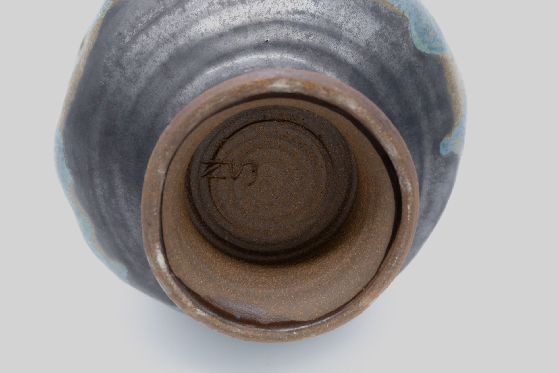 Top view of a spherical studio pottery vase with indented body, multi-colored glaze, and signature on the bottom.