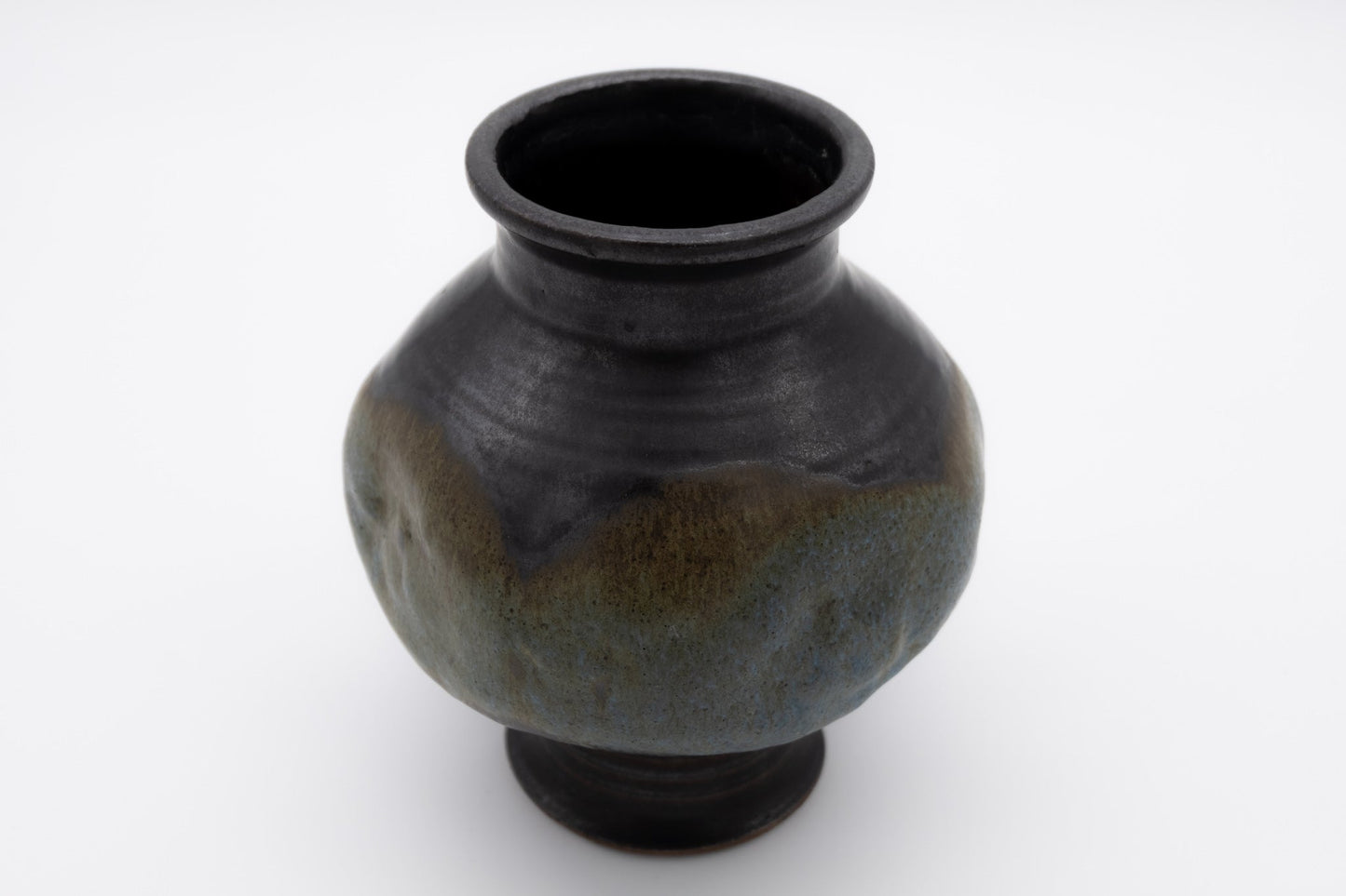 Spherical indented pottery vase with a multi-colored glaze, studio-crafted and signed on the bottom.