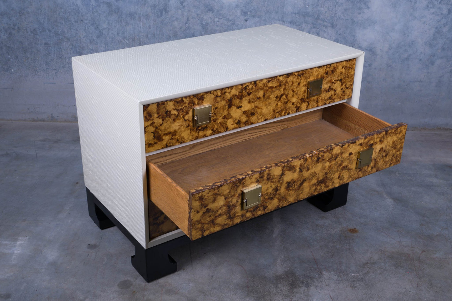James Mont style faux tortoiseshell dresser with two drawers, white riveted exterior, and black lacquered carved feet base.