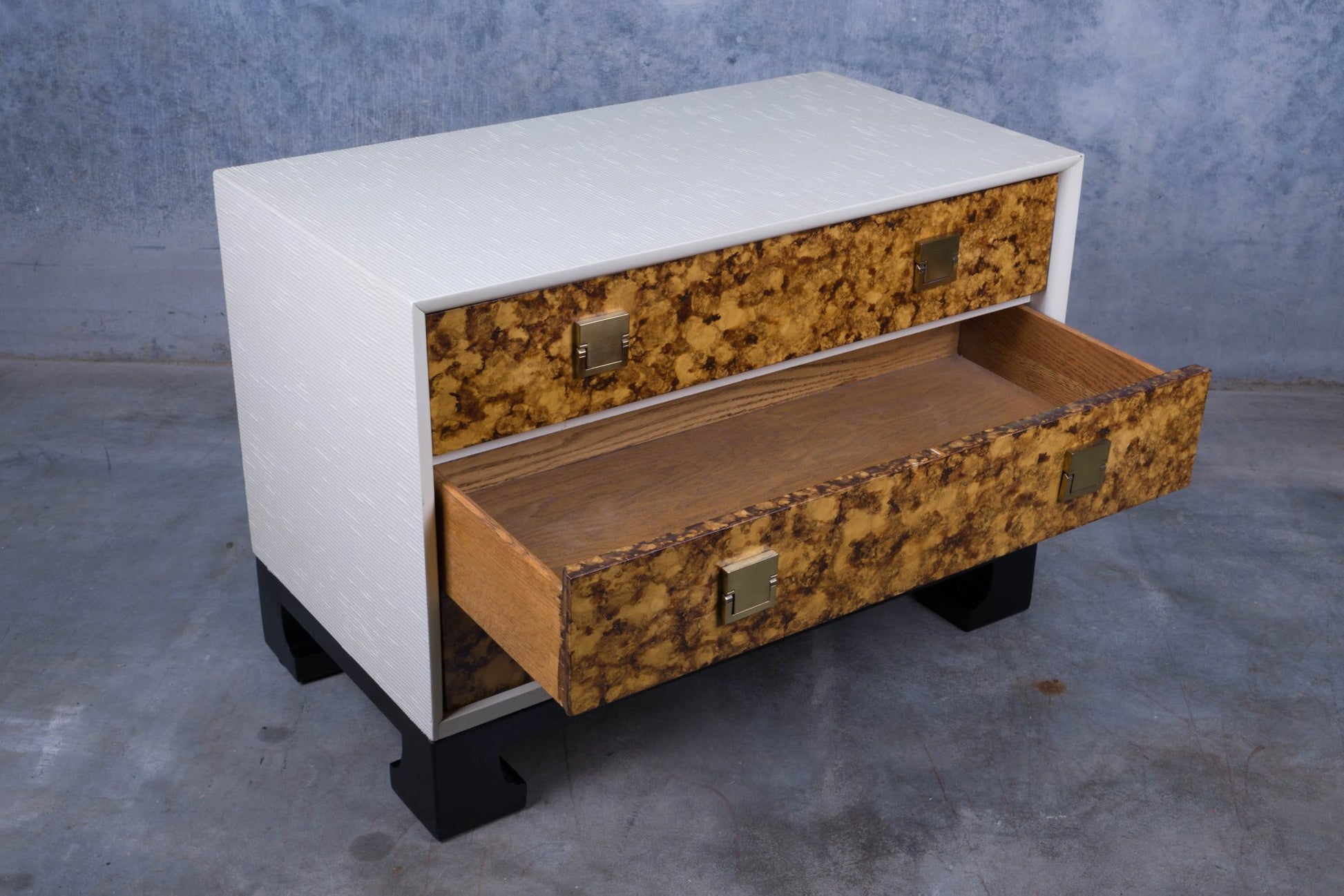 James Mont style faux tortoiseshell dresser with two drawers, white riveted exterior, and black lacquered carved feet base.