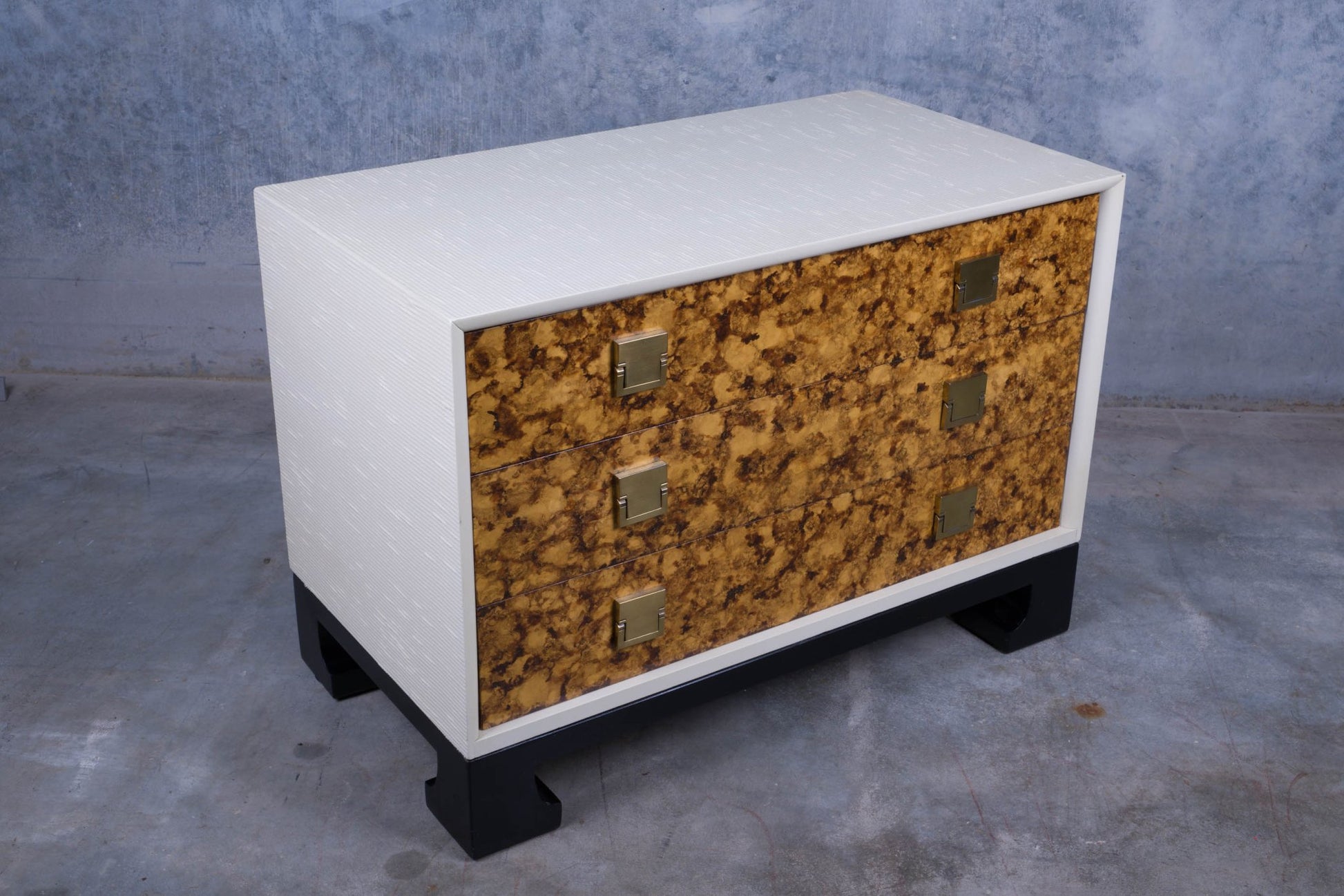 James Mont style three drawer faux tortoiseshell dresser with white body and black lacquered carved feet base