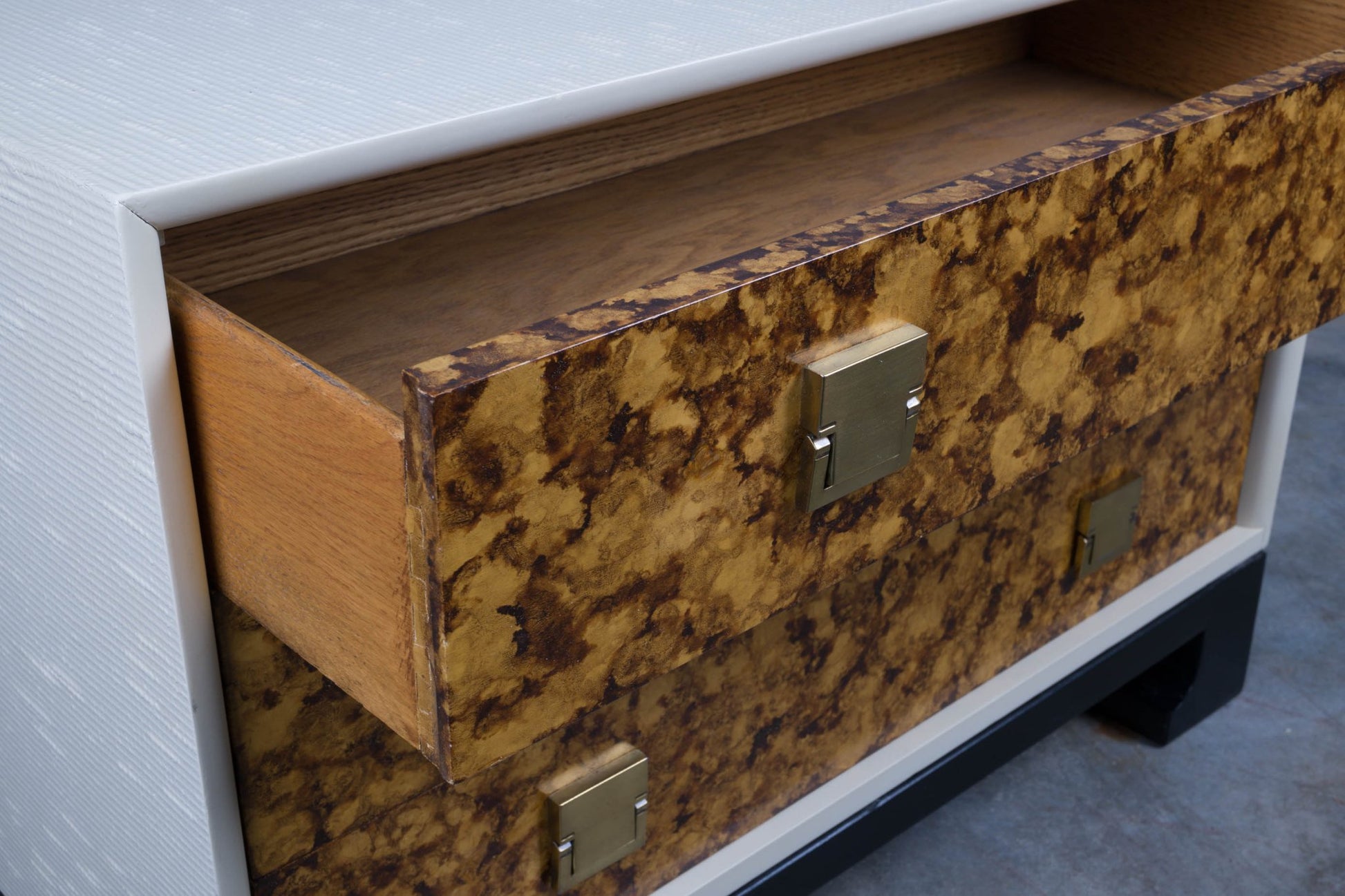 Close-up of mid-century modern faux tortoiseshell dresser drawer with brass hardware and black lacquered base