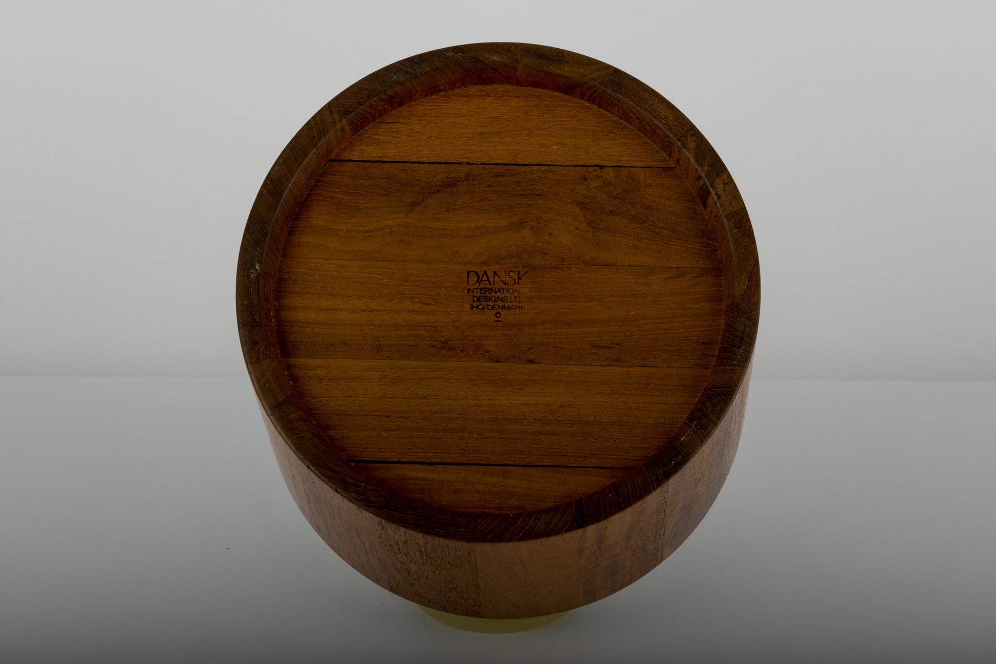 Bottom view of Jens Quistgaard teak ice bucket from the 1970s with Dansk Denmark maker’s mark on a reflective surface