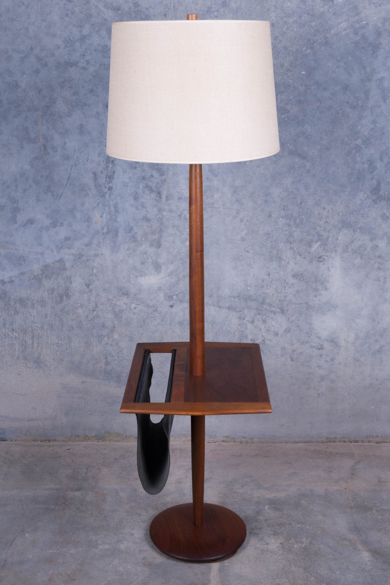 1960s Laurel floor lamp with walnut wood side table and black leather magazine sling against gray concrete wall