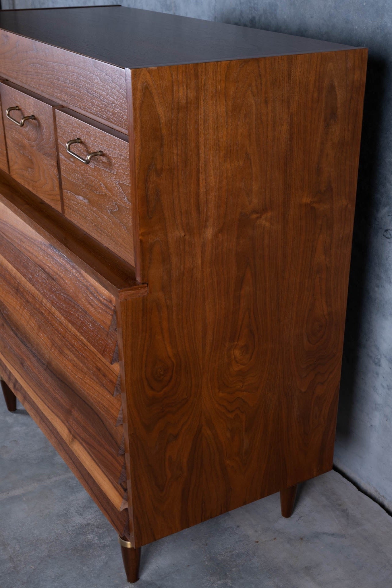 Mid-century modern walnut highboy dresser with louvered drawer fronts and brass handles on tapered legs.