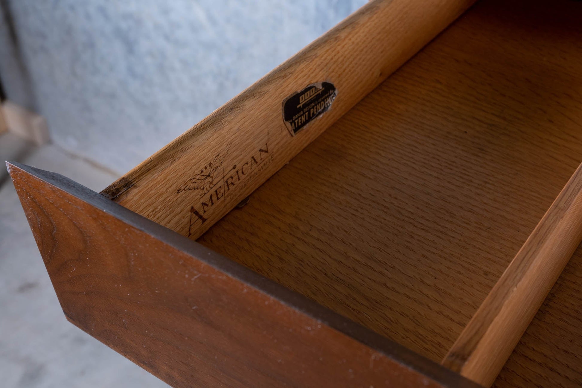 Interior view of open walnut drawer with American of Martinsville and vintage labels on side panel