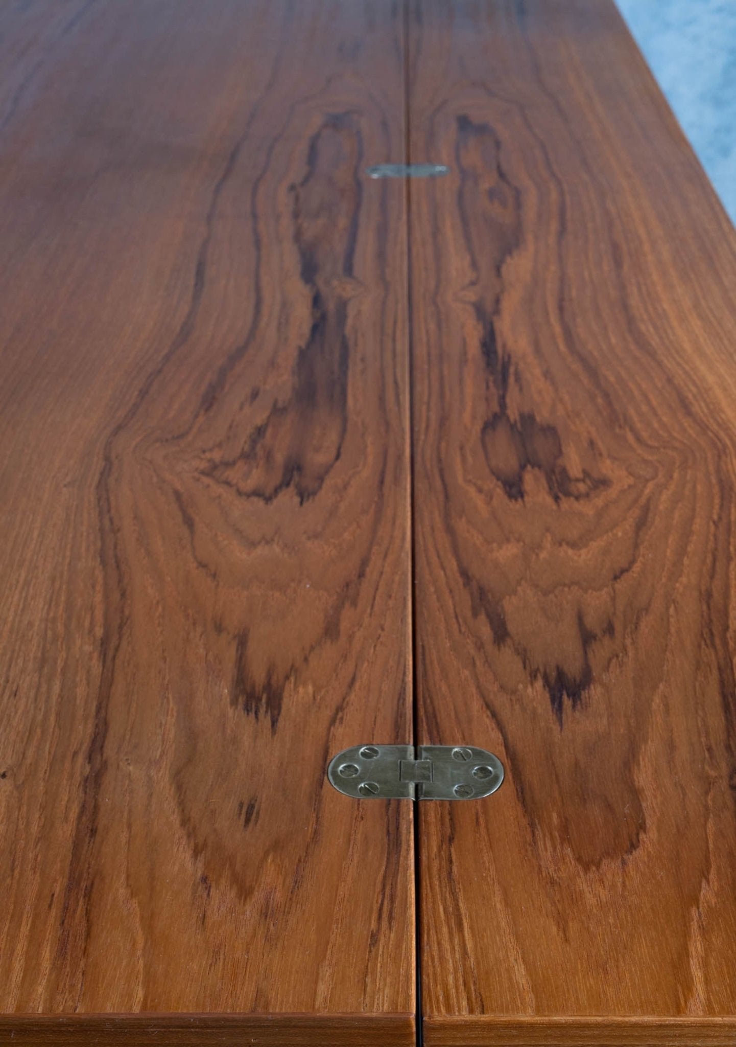 Close-up of rosewood flip-top desk surface with visible wood grain patterns and metal hinge in the center